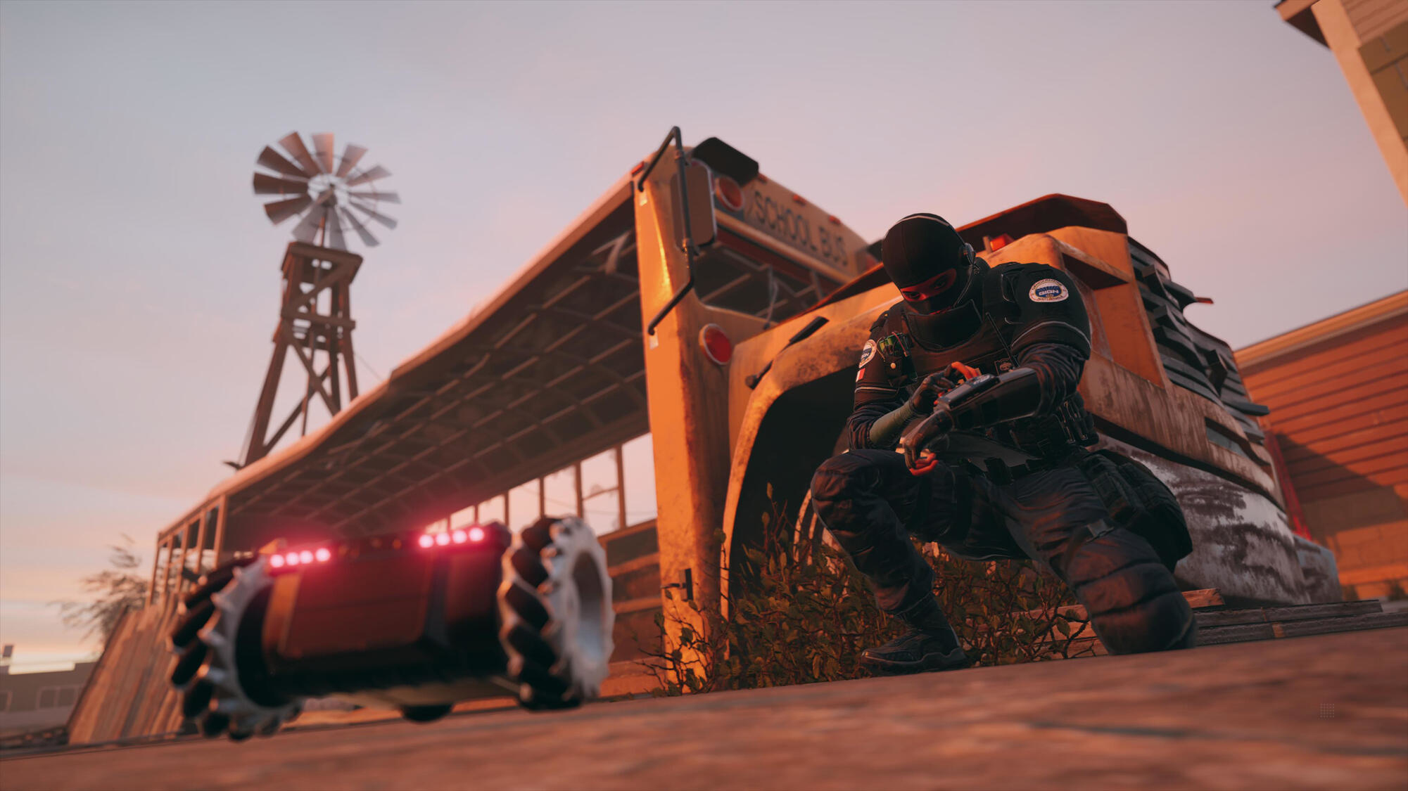 Żołnierz kuca w pobliżu autobusu. W tle wiatrak i budynek, zachód słońca.