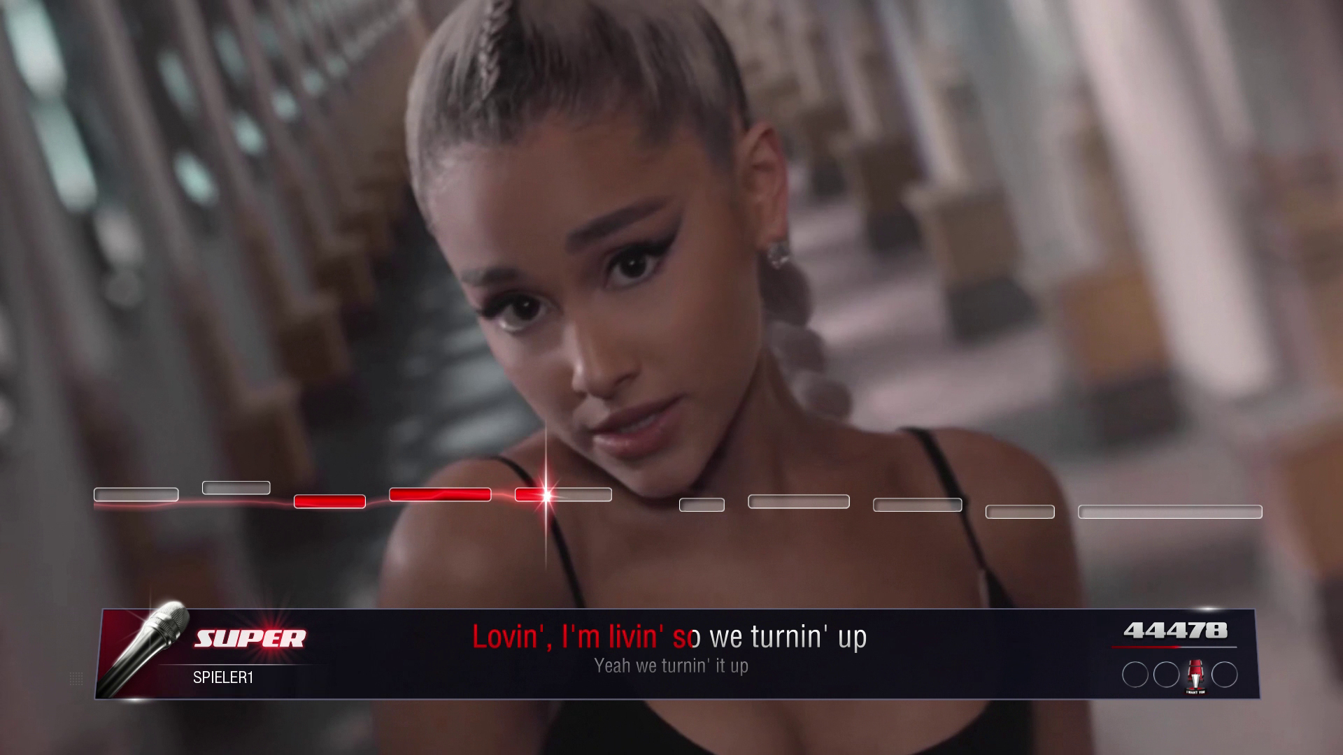 Ariana Grande śpiewa w grze karaoke. Wynik i tekst są wyświetlane.