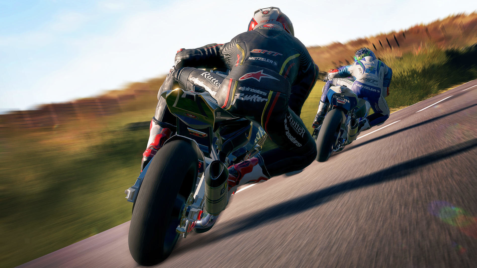 Due moto da corsa su strada, piloti con equipaggiamento completo, sfondo sfocato della strada e del cielo.