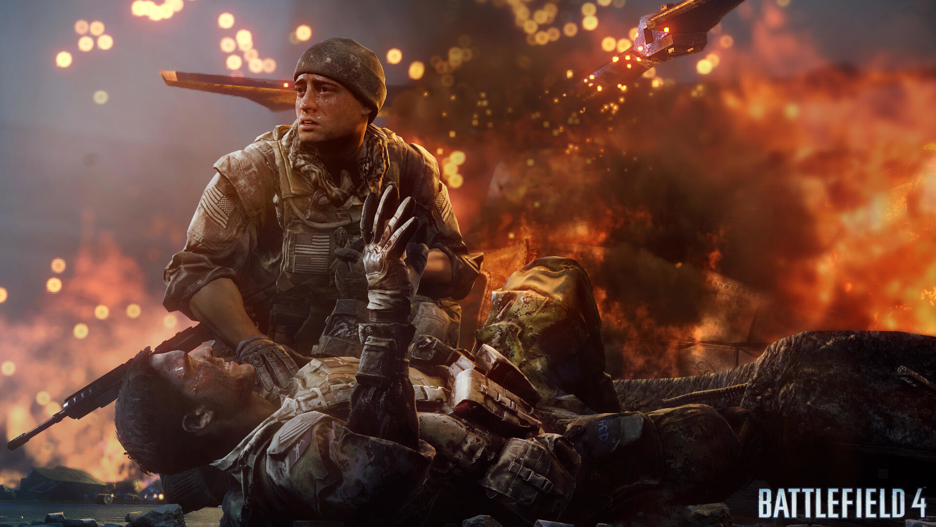 Un soldato aiuta un commilitone ferito in un campo di battaglia con fuoco sullo sfondo. Da Battlefield 4.