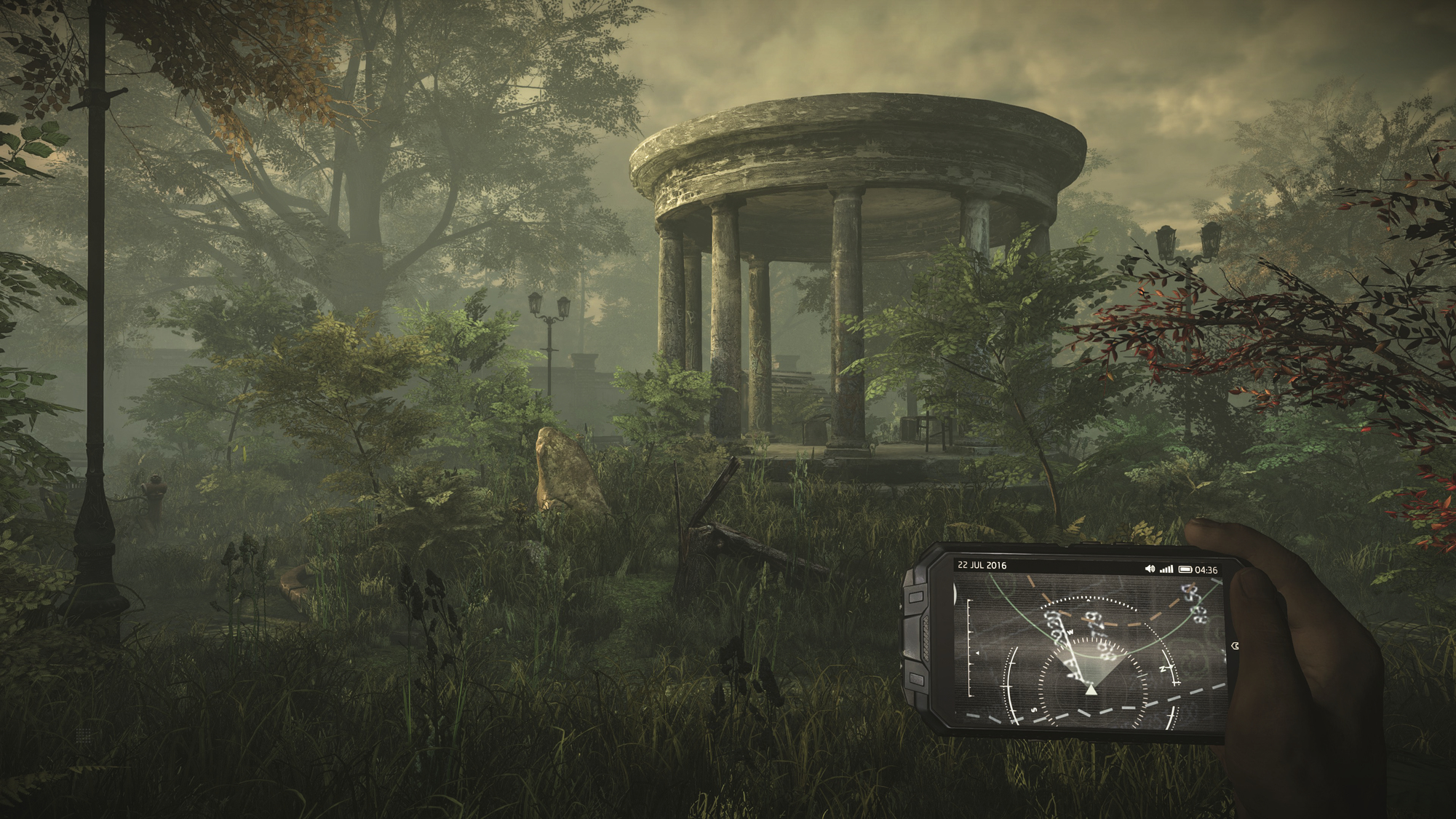 Osoba trzymająca urządzenie z mapą w parku. Kamienna konstrukcja w tle.