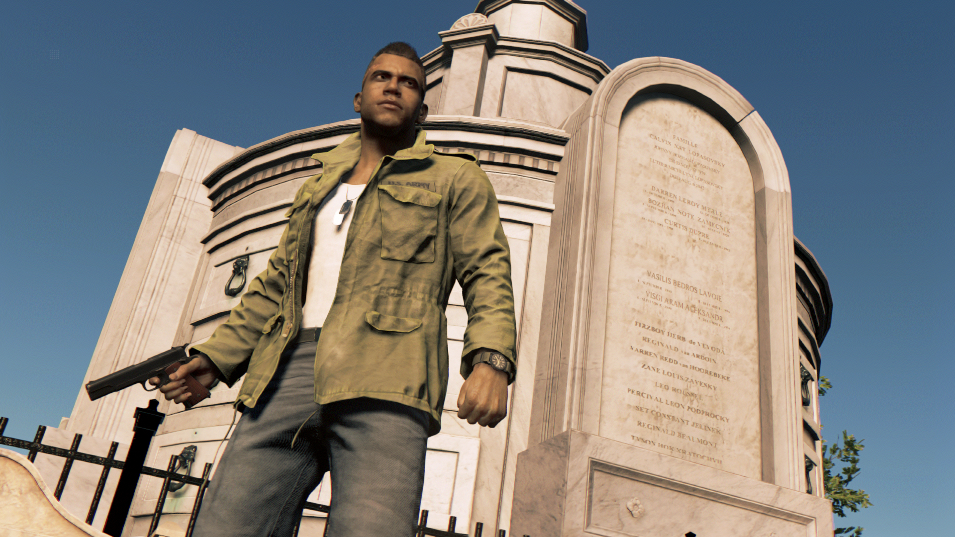 Mężczyzna z bronią stoi przed pomnikiem. Ma na sobie kurtkę i dżinsy. Niebieskie niebo w tle.