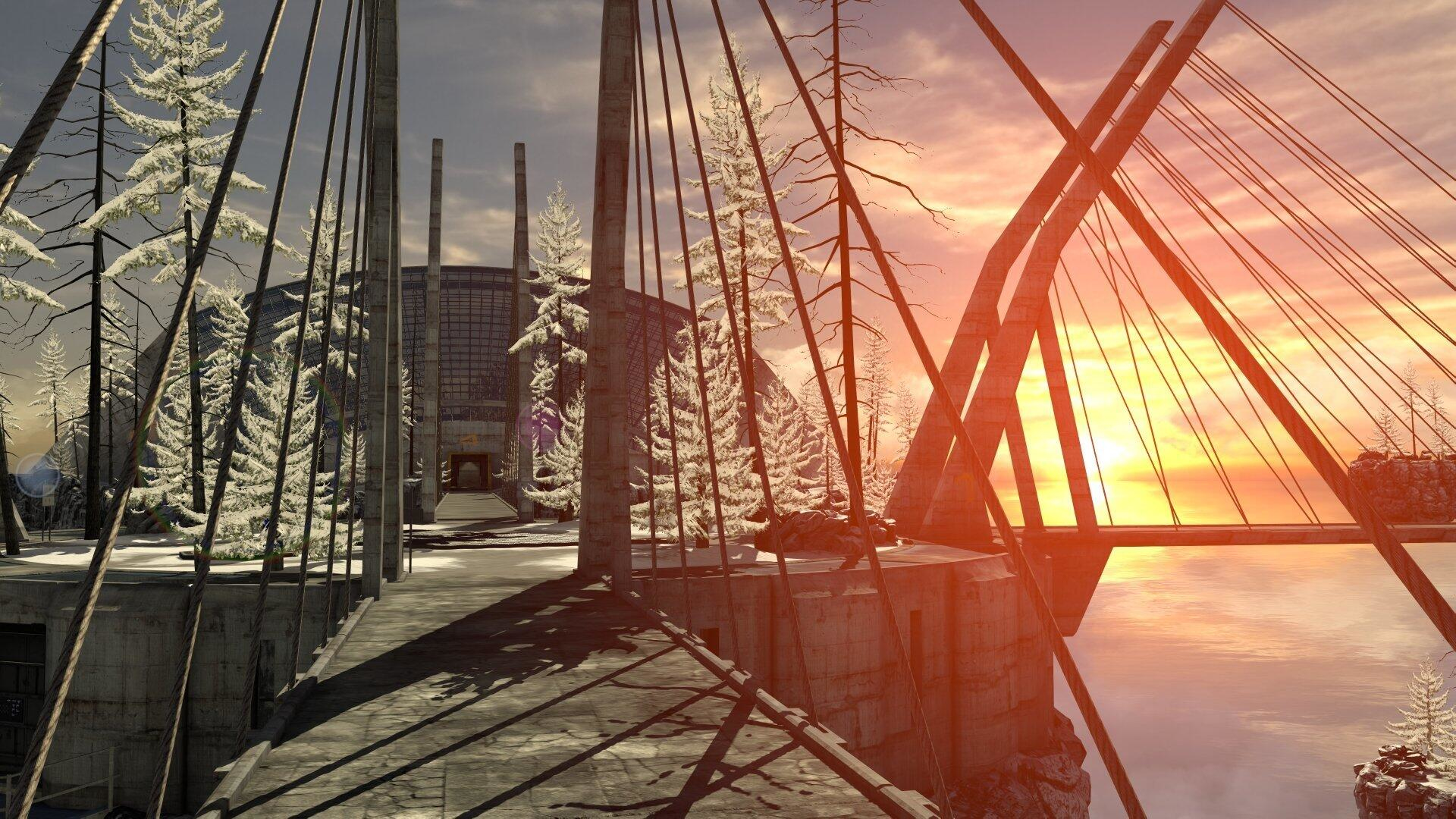Eine Brücke über Wasser mit Sonnenuntergang im Hintergrund und schneebedeckten Bäumen.