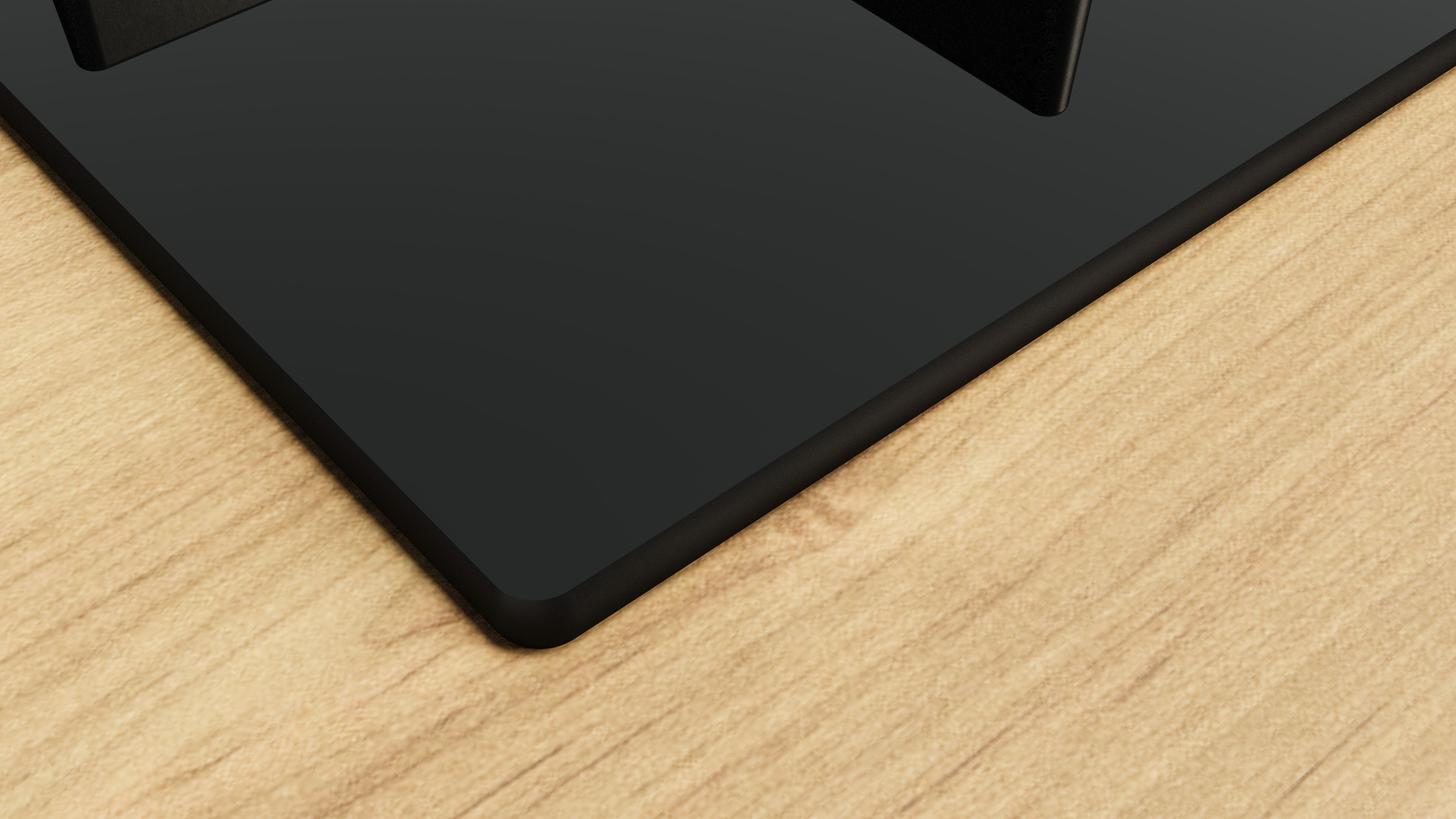 Zbliżenie czarnej płyty grzewczej na jasnej drewnianej powierzchni. Płyta grzewcza ma ciemną krawędź.