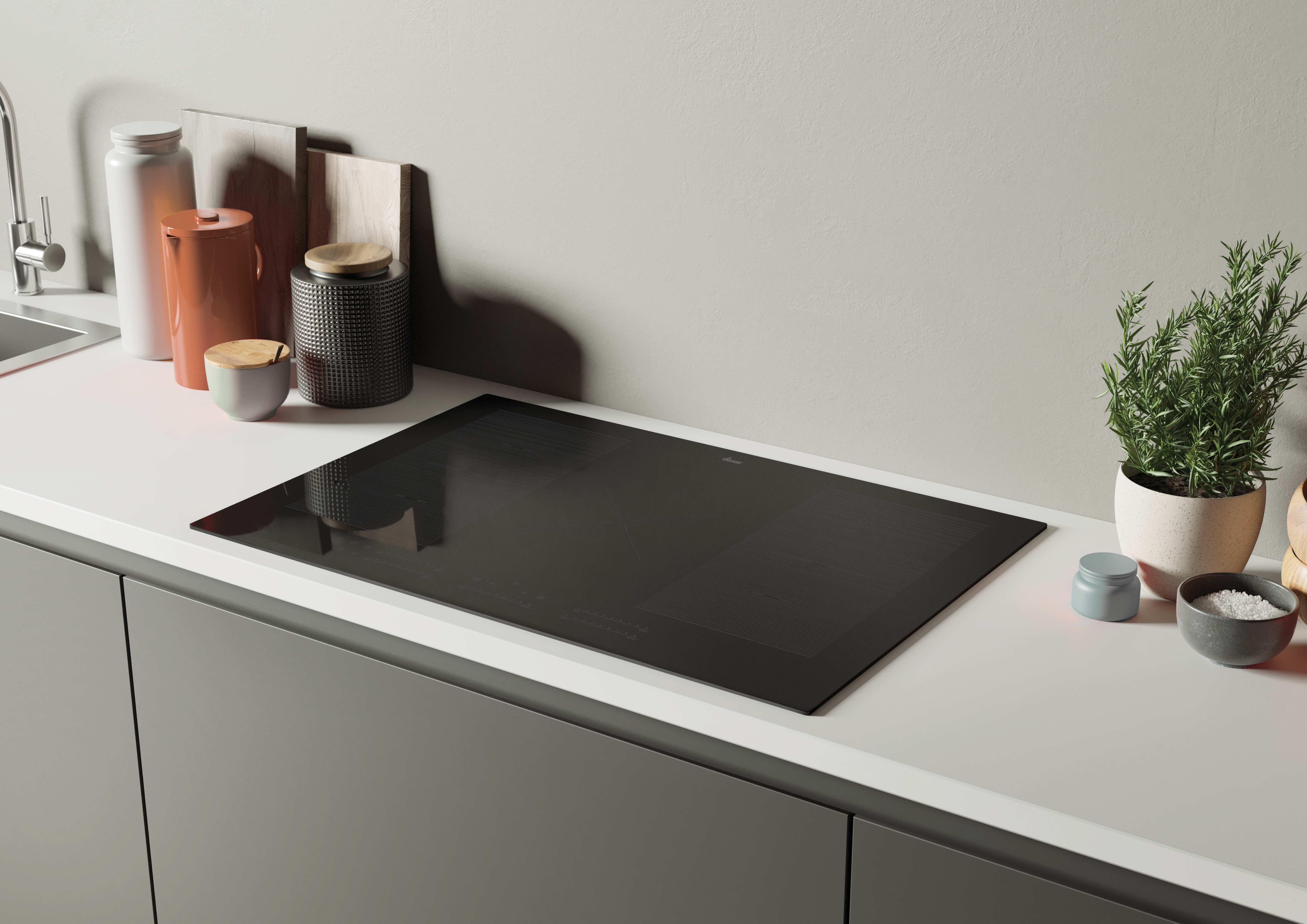 Un moderno piano cucina con un piano cottura nero installato. Sono presenti vari utensili da cucina e decorazioni.