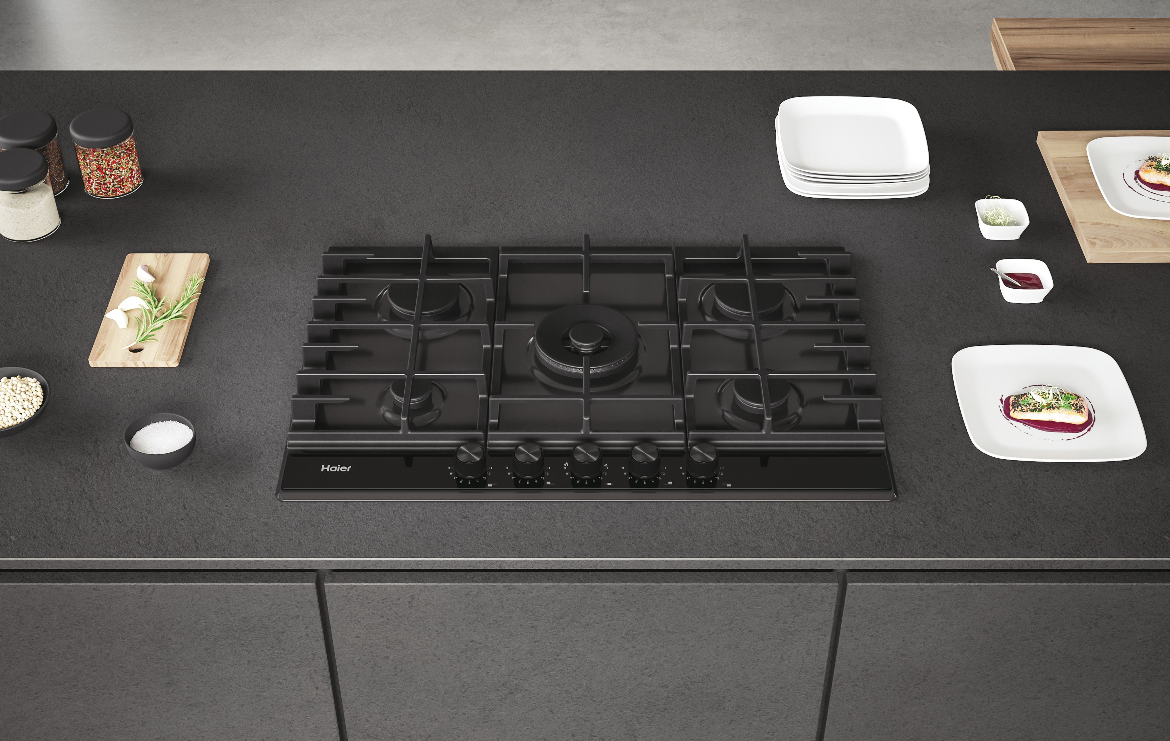 Vista cenital de una encimera de cocina. Placa de gas negra con cinco quemadores, platos y comida.