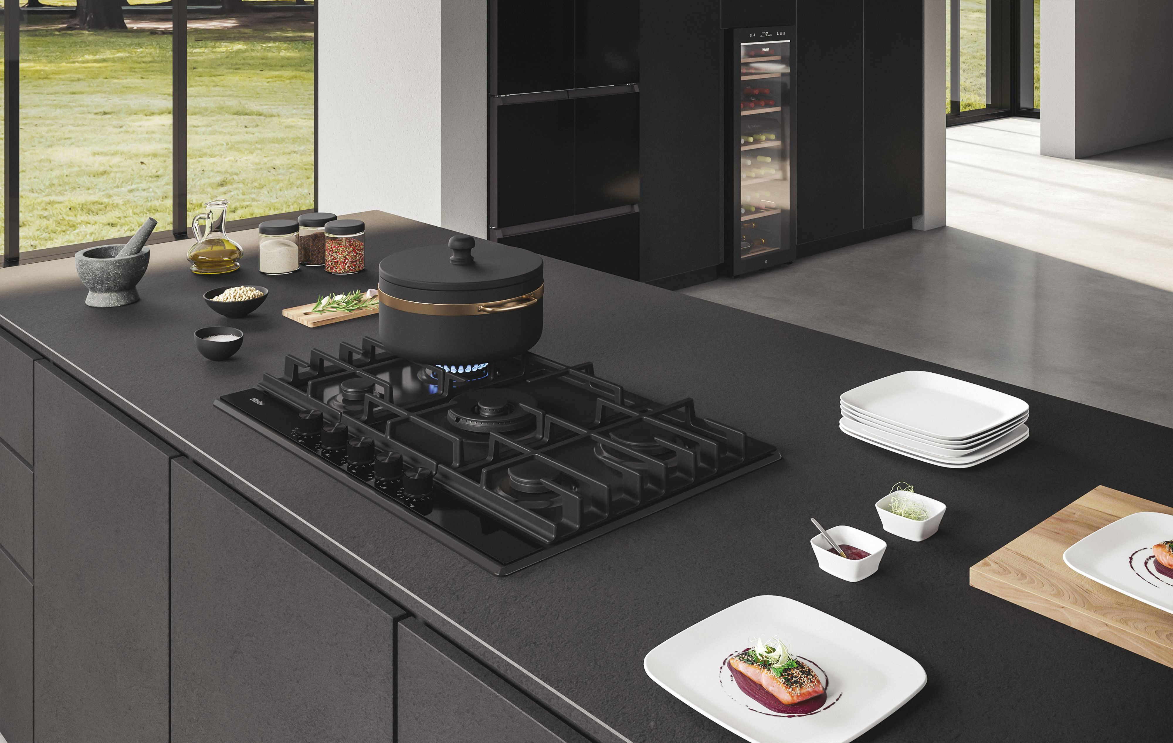 Cocina con encimera negra, placa de gas negra con llama azul y platos con comida.