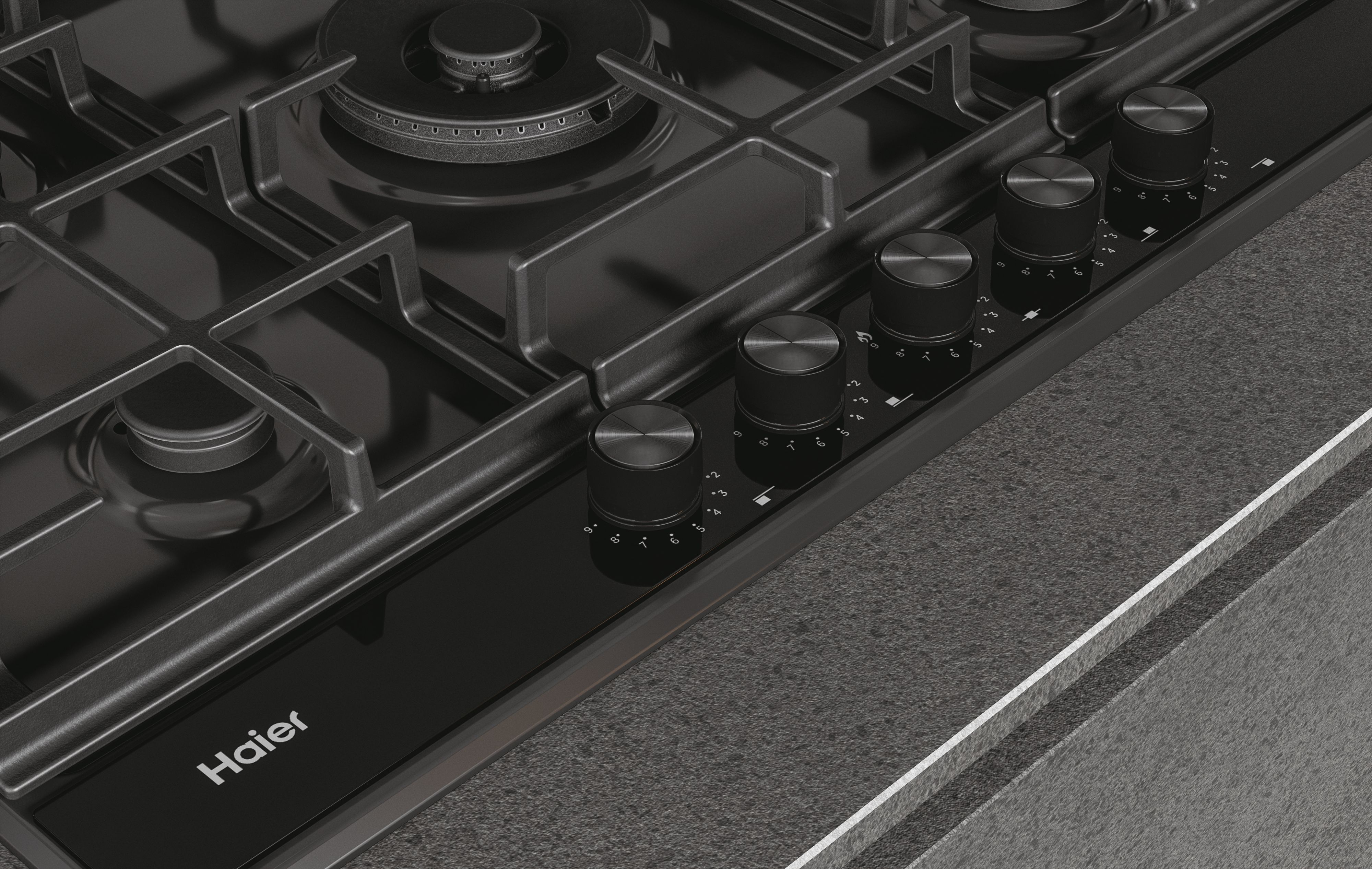 Primer plano de una encimera de gas negra con mandos. La marca Haier es visible.