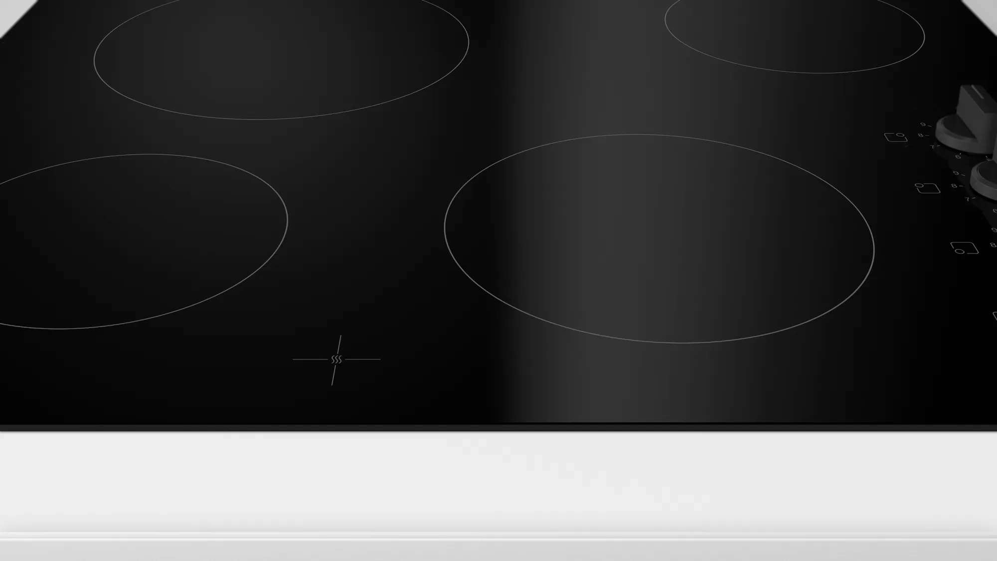 Gros plan sur une table de cuisson en verre noir avec quatre éléments chauffants circulaires.