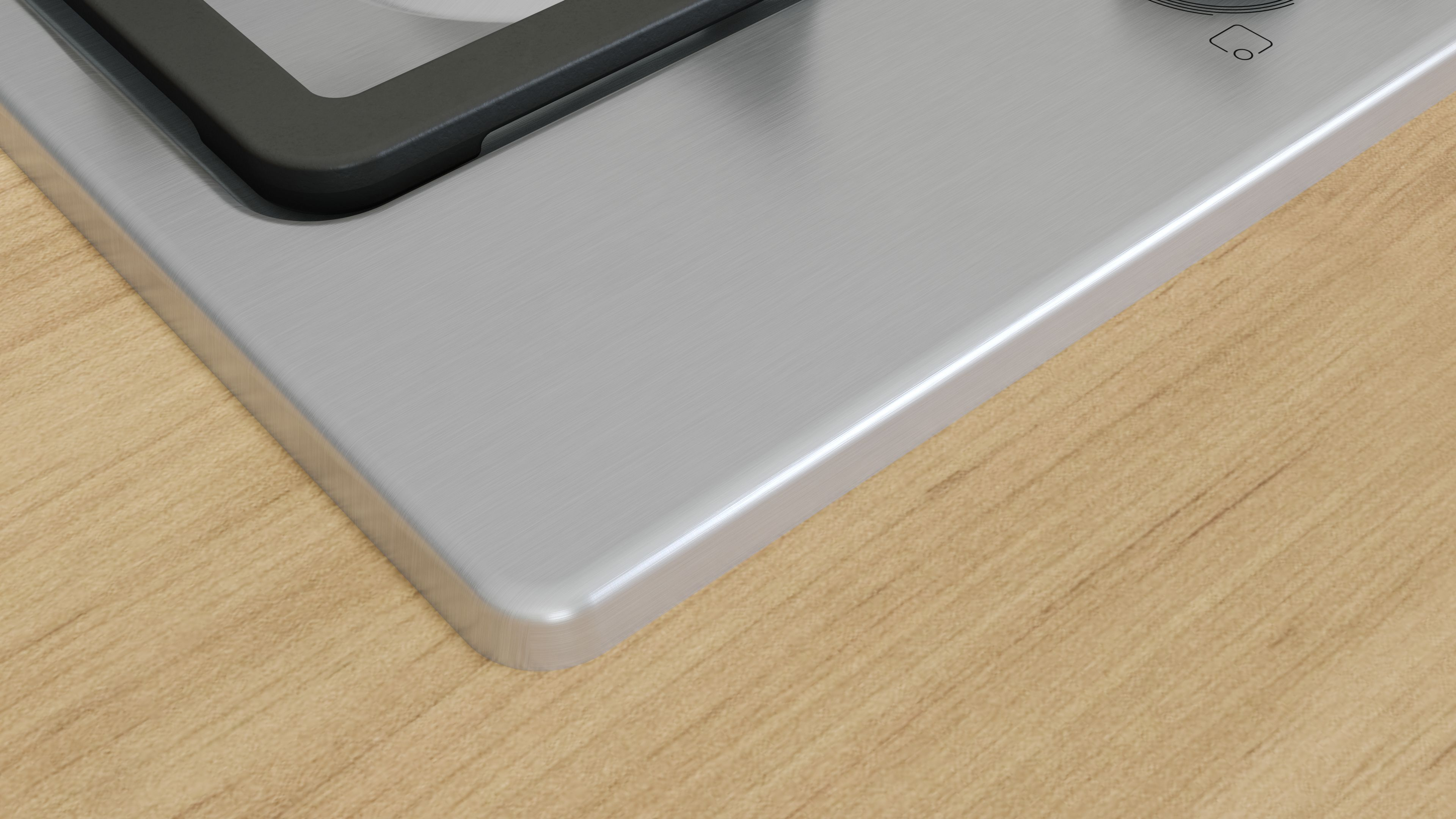 Zbliżenie na róg płyty gazowej. Srebrna powierzchnia i drewniany blat. Białe tło.