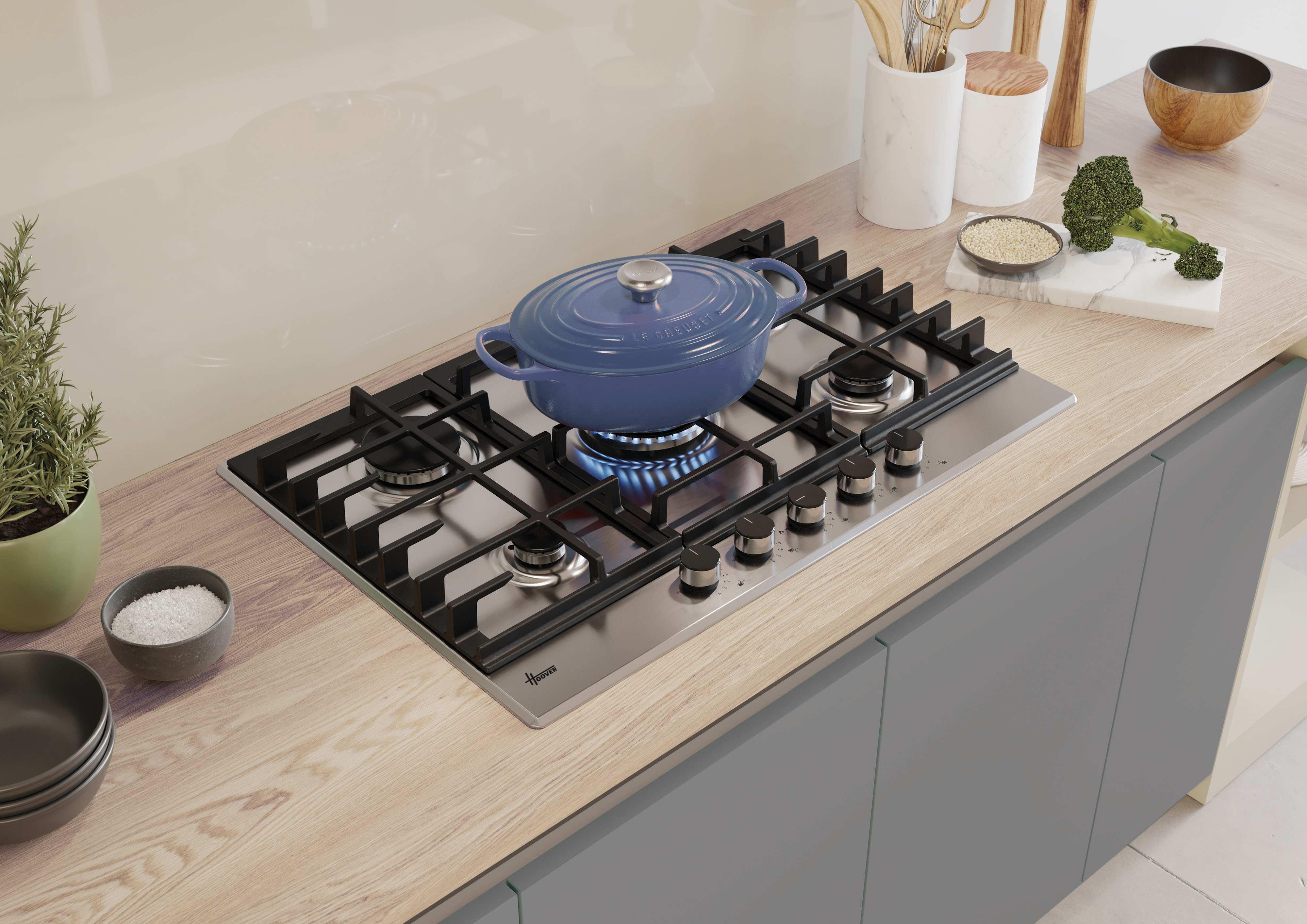 Una pentola blu su un piano cottura a gas in acciaio inox, con utensili da cucina accanto.