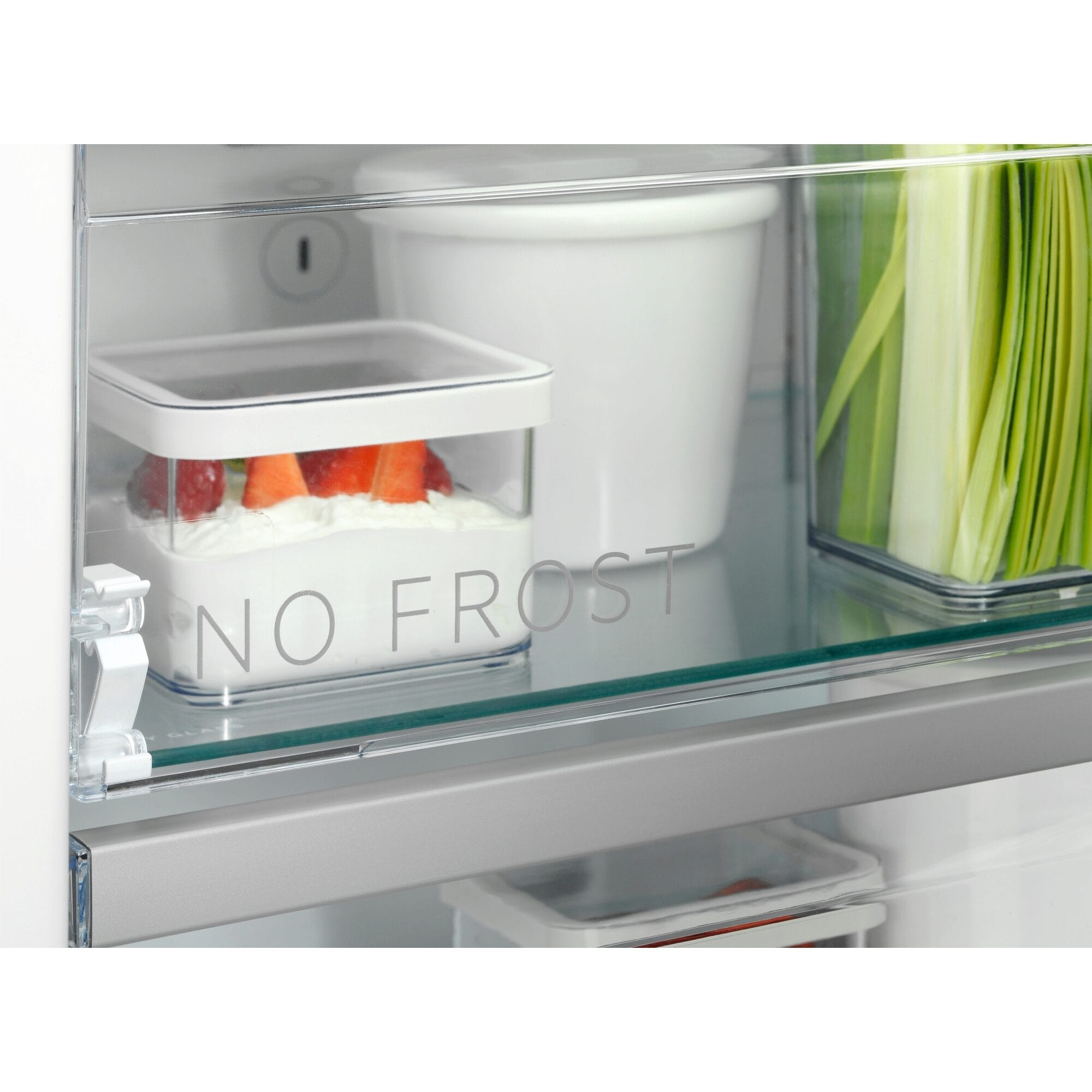 Primer plano del interior de un frigorífico, mostrando recipientes transparentes con comida, etiquetados 'NO FROST'.