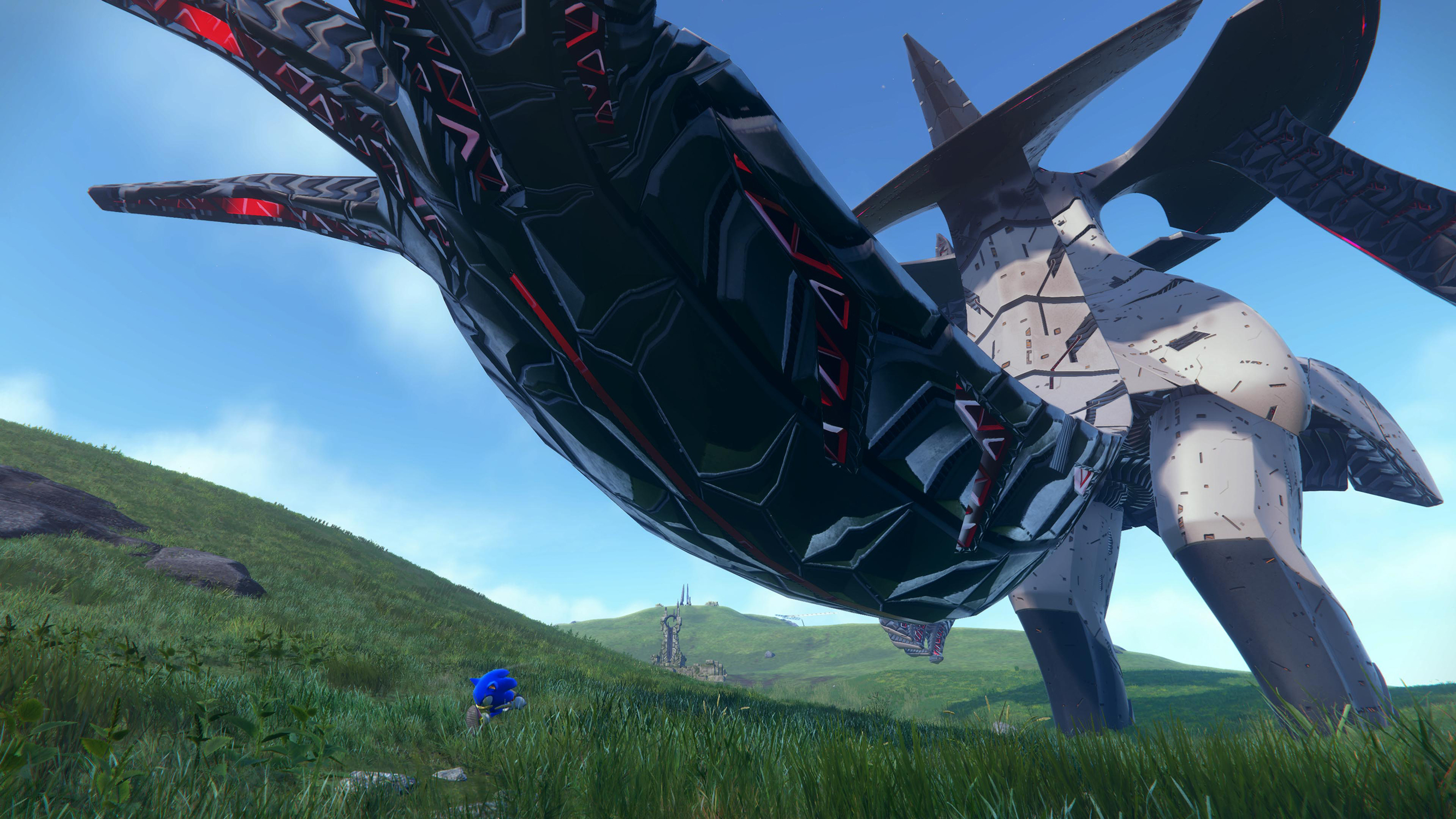Sonic the Hedgehog che corre in un campo verde con una grande struttura metallica.