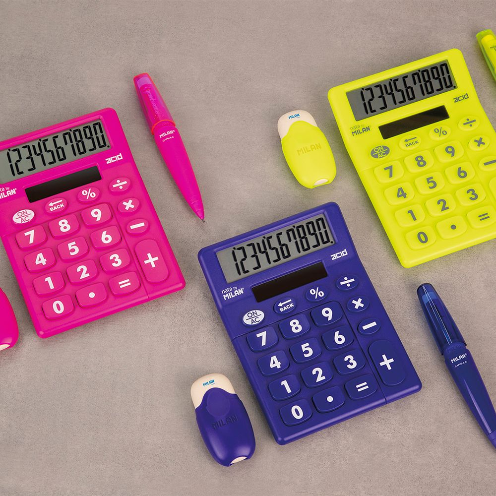 Różne kolorowe kalkulatory, gumki i długopisy rozrzucone na szarej powierzchni.