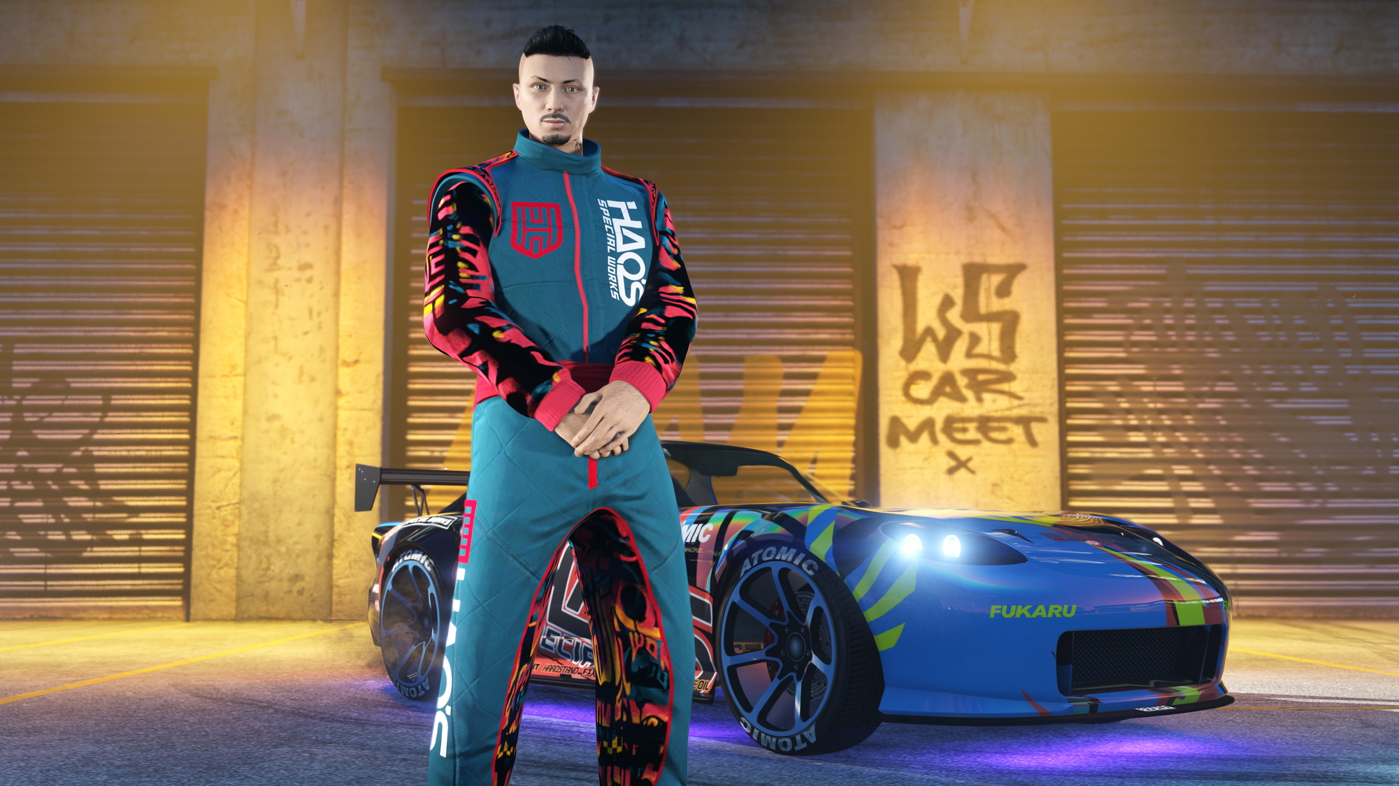 Mężczyzna w turkusowym stroju stoi obok niebieskiego samochodu przed garażem. Graffiti na ścianie.