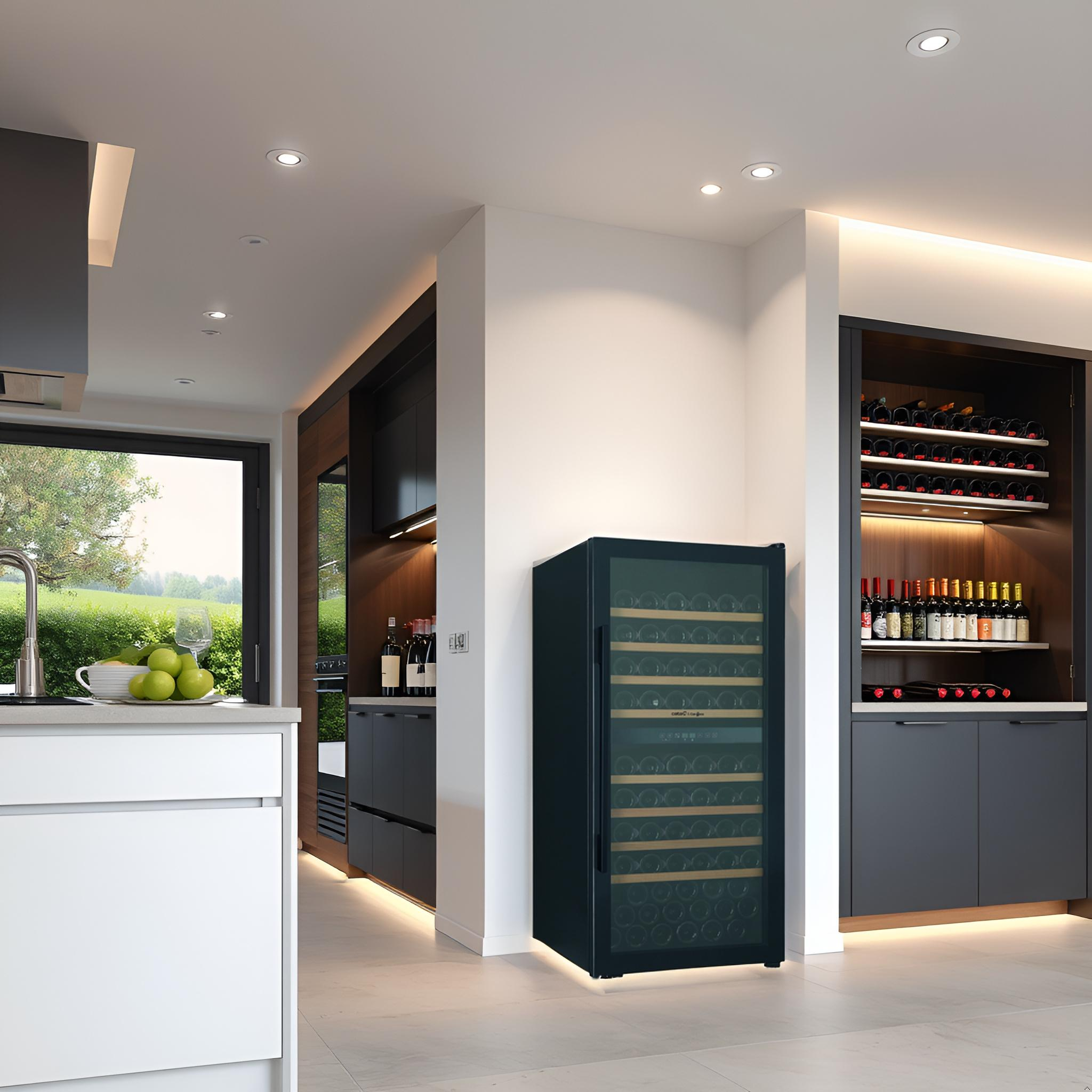 Interior de cocina con vinoteca, armarios blancos y gris oscuro, y una ventana con vista al jardín.
