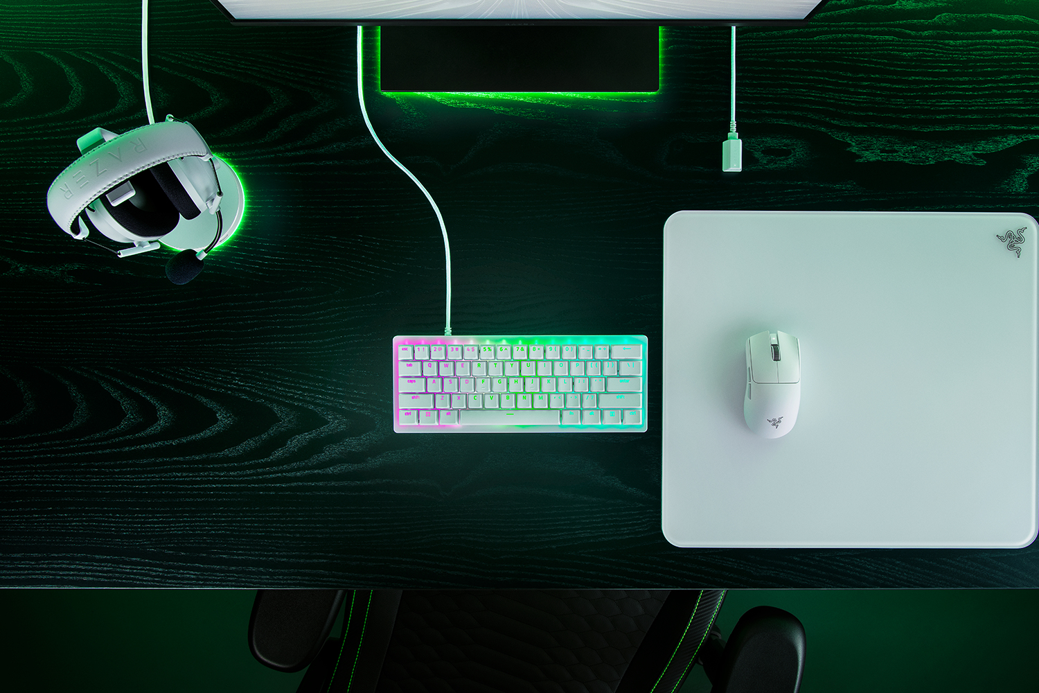 Configuration de jeu avec clavier, souris, casque et moniteur. Bureau noir avec éclairage ambiant vert.