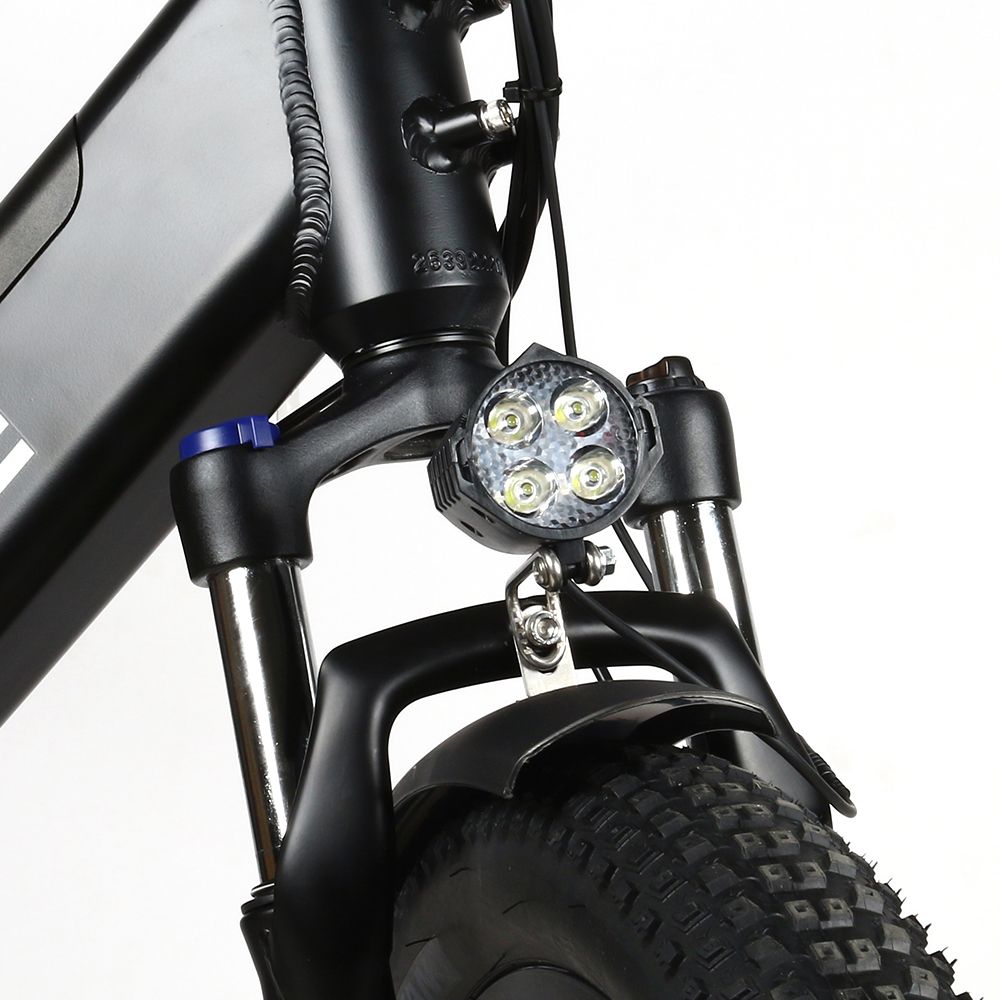 Zbliżenie na przód roweru elektrycznego, w tym reflektor i zawieszenie.