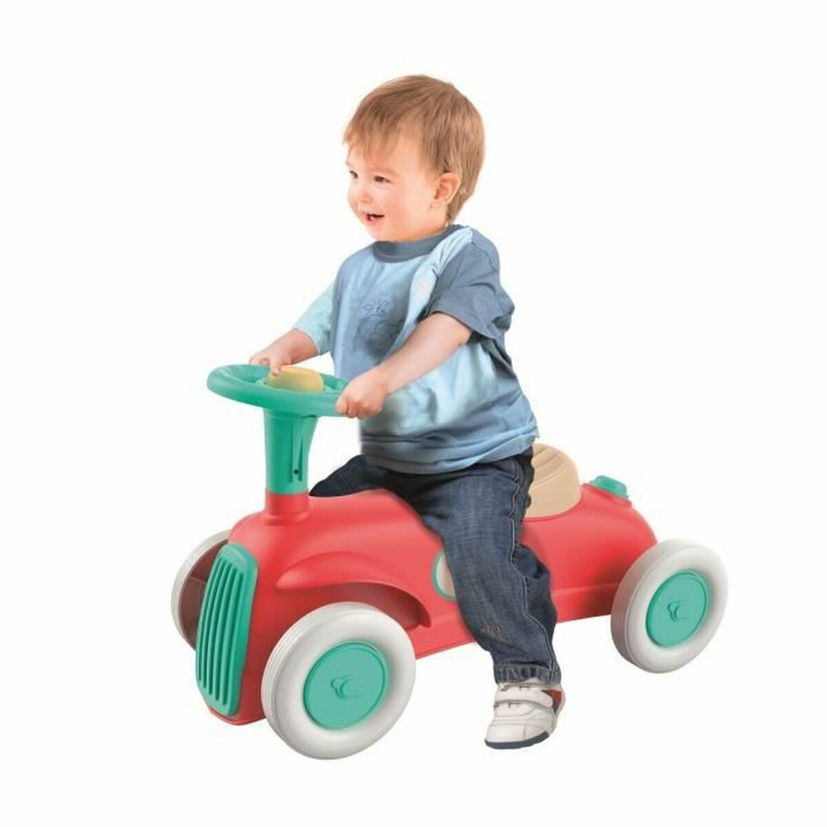 Un bambino su un'auto giocattolo rossa. L'auto ha un volante verde e pneumatici bianchi.