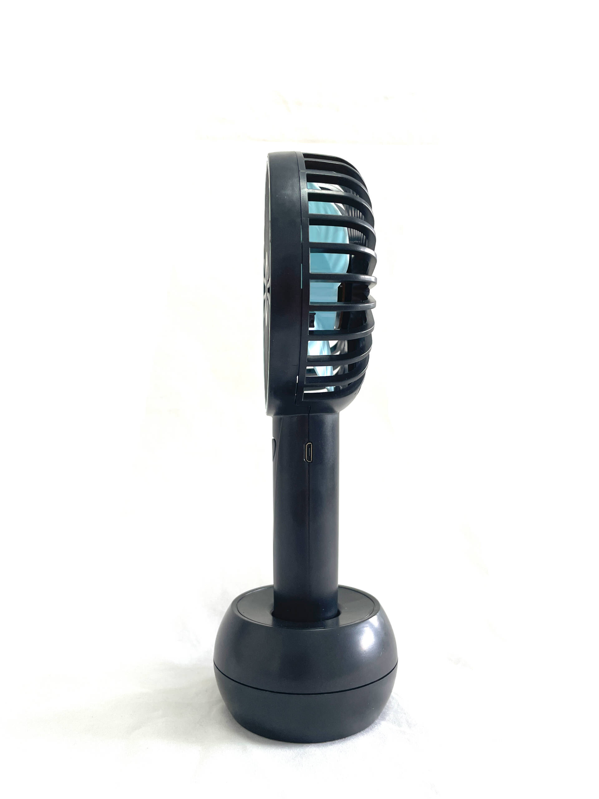 Seitenansicht eines schwarzen Handventilators mit blauen Flügeln auf weißem Hintergrund, mit USB-Anschluss.