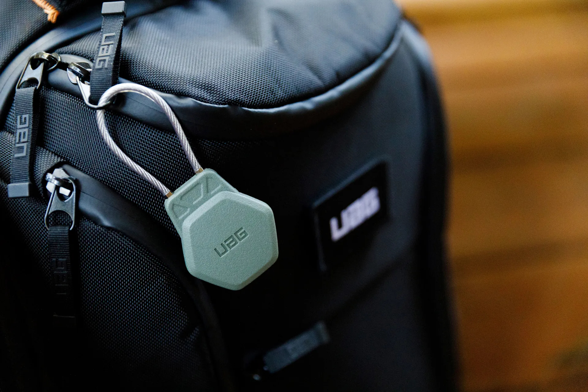 Grünes Schloss an einem schwarzen Rucksack befestigt. Das Schloss sagt 'UAG'.