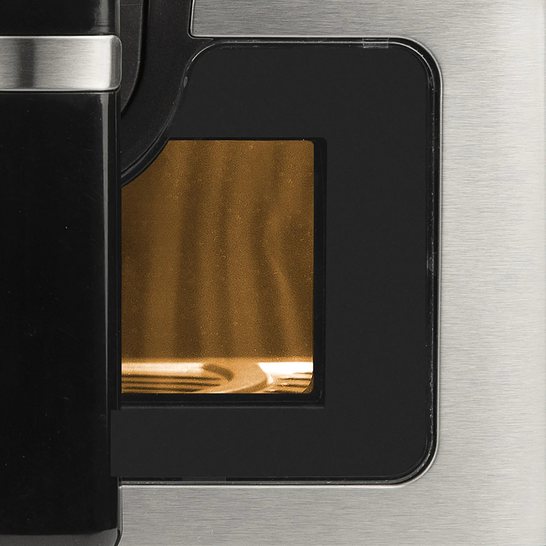 Zbliżenie komory pieczenia frytkownicy powietrznej. Brązowe wnętrze. Czarna ramka i srebrne detale.