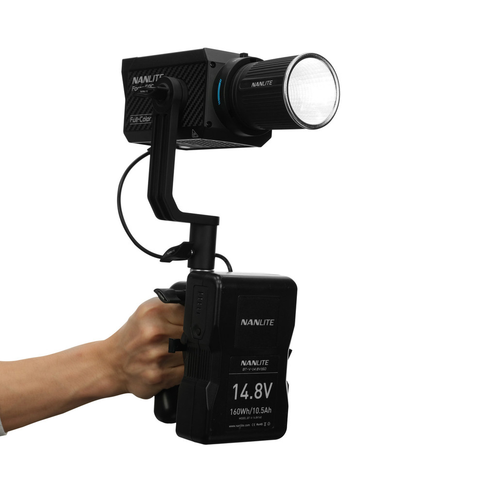 Hand holding black Nanlite Forza 60C LED light with battery attached, white bg.