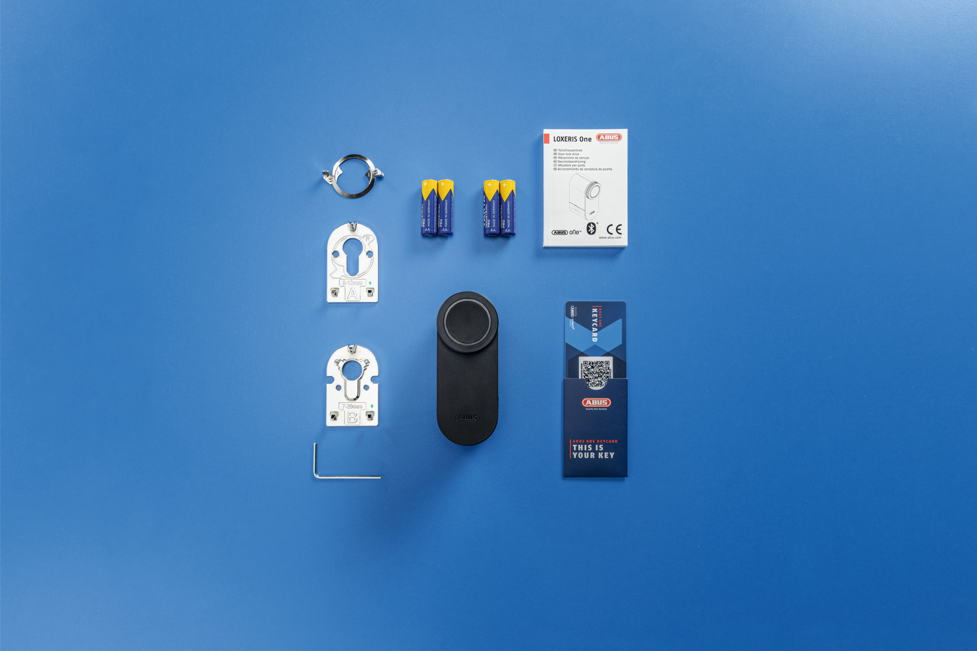 Widok z góry na elementy inteligentnego zamka na niebieskiej powierzchni. Zawiera zamek, kartę klucza, baterie i akcesoria.