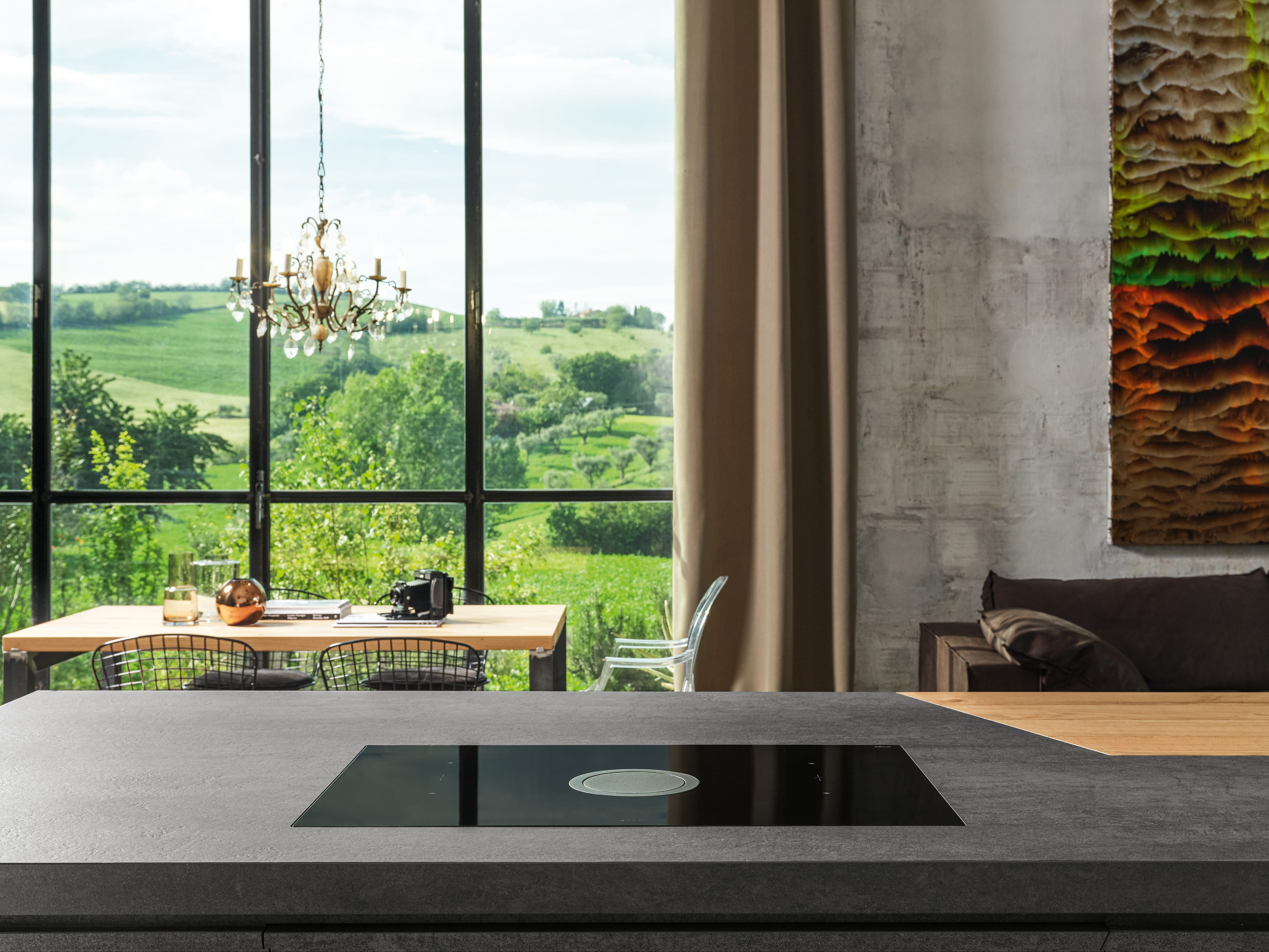 Cucina moderna con vista su un paesaggio attraverso una grande finestra. Un'isola cucina è a fuoco.