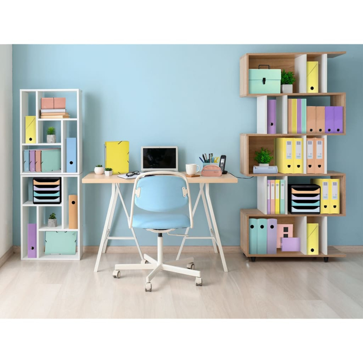 Konfiguracja biurka w biurze z biurkiem, laptopem, krzesłem, półkami i różnymi artykułami biurowymi, jasnoniebieska ściana.