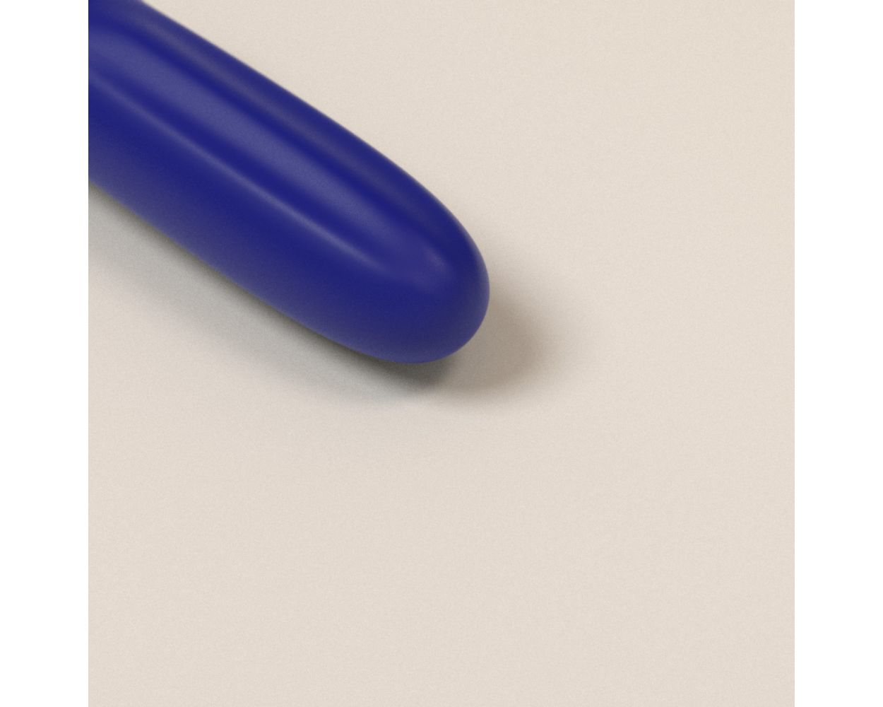 Primer plano de la punta de un vibrador azul sobre un fondo beige claro.