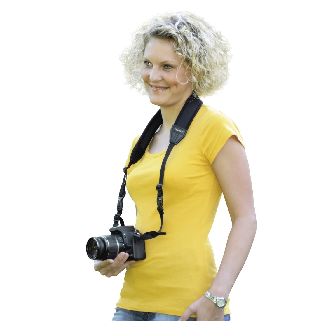 Una donna con i capelli biondi ricci che indossa una maglietta gialla, tiene una macchina fotografica con una cinghia.