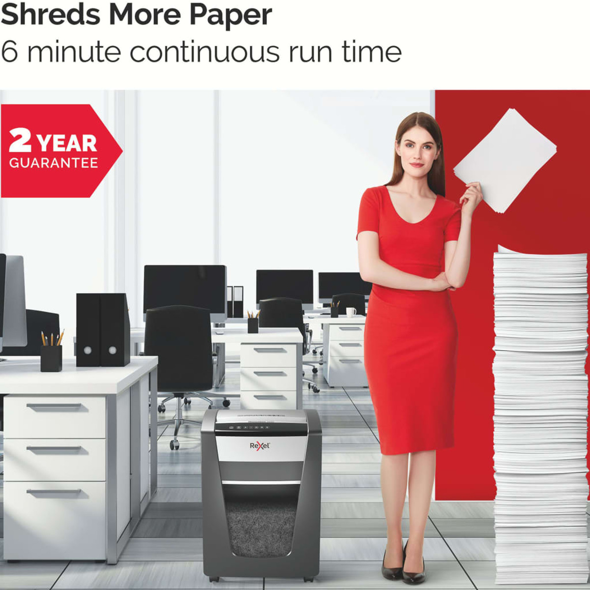 Kobieta w czerwonej sukience trzymająca papier, obok niszczarki i stosu papierów, w biurze.