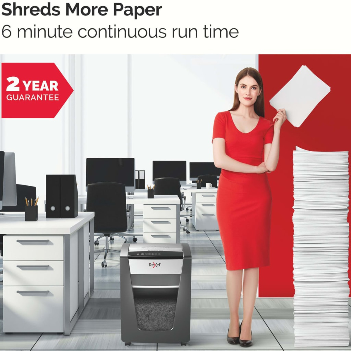 Kobieta w czerwonej sukience stoi obok niszczarki do papieru w otoczeniu biurowym.