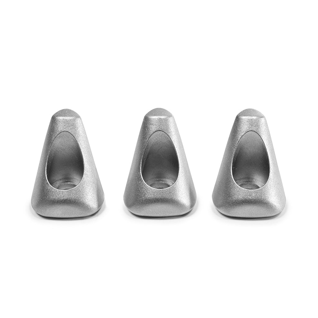Tre oggetti triangolari argentati con fori. Sfondo bianco. Forme astratte.