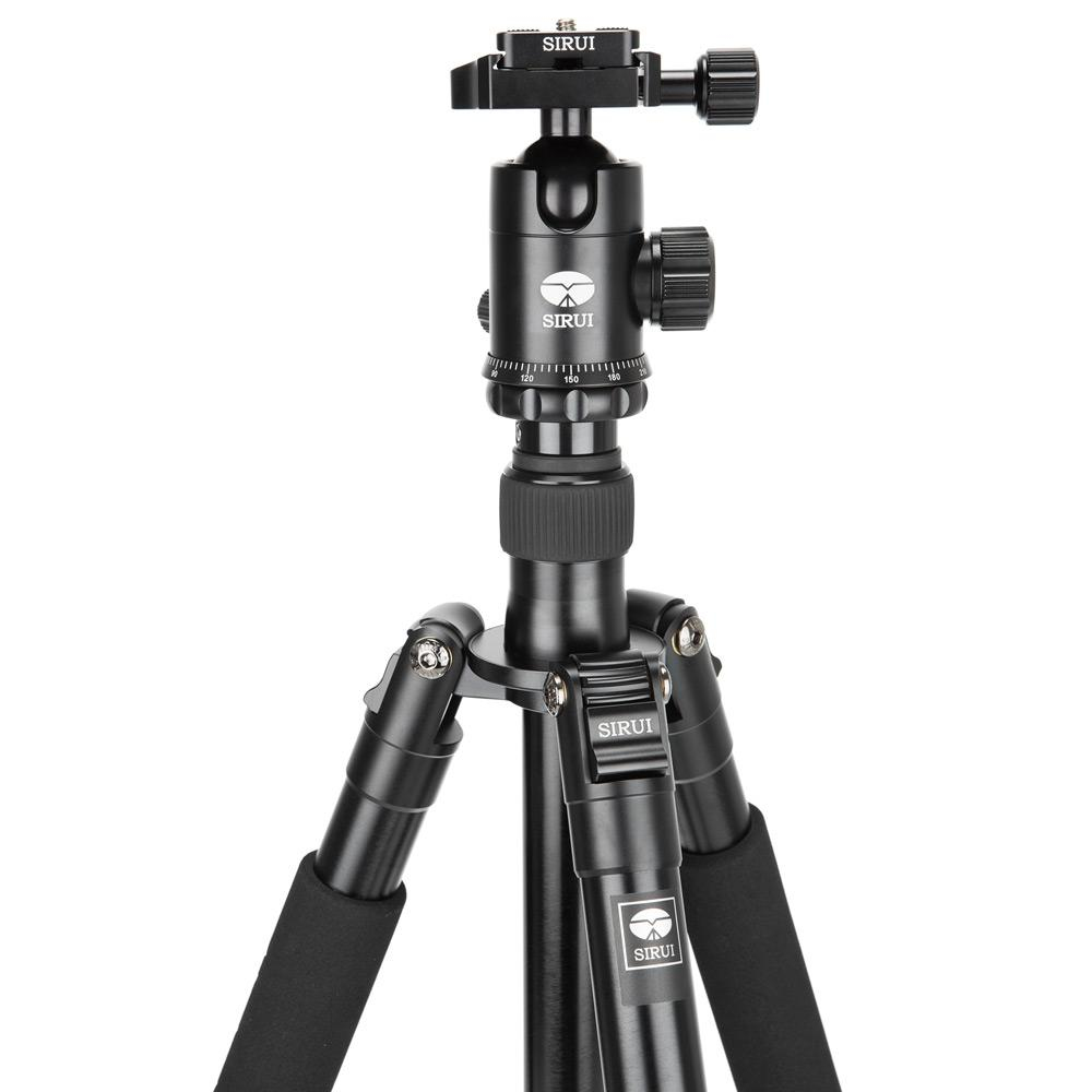 Close-up of a black tripod head with Sirui logo. The legs are extended.