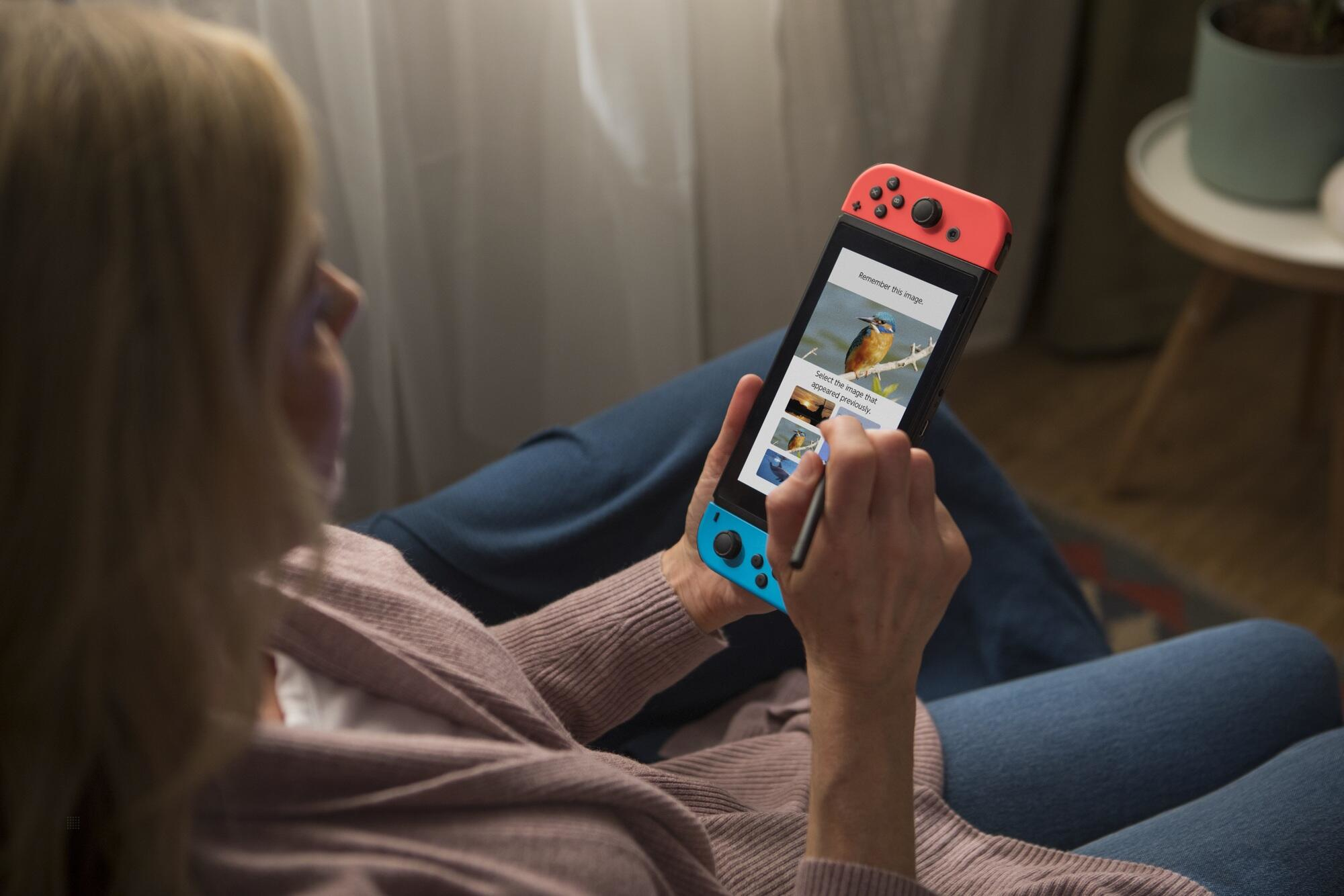 Kobieta korzystająca z Nintendo Switch. Trzyma konsolę z rysikiem. Widoczny ekran gry.