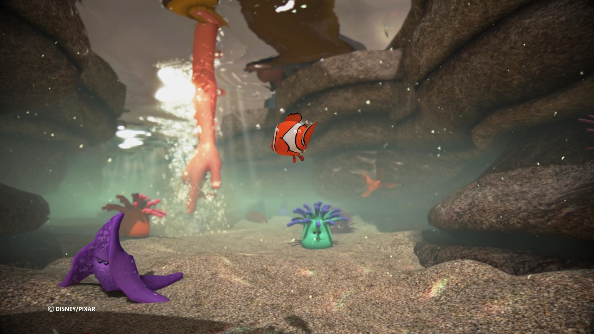 Scena subacquea: Nemo nuota. Rocce e coralli visibili. Una mano in acqua.