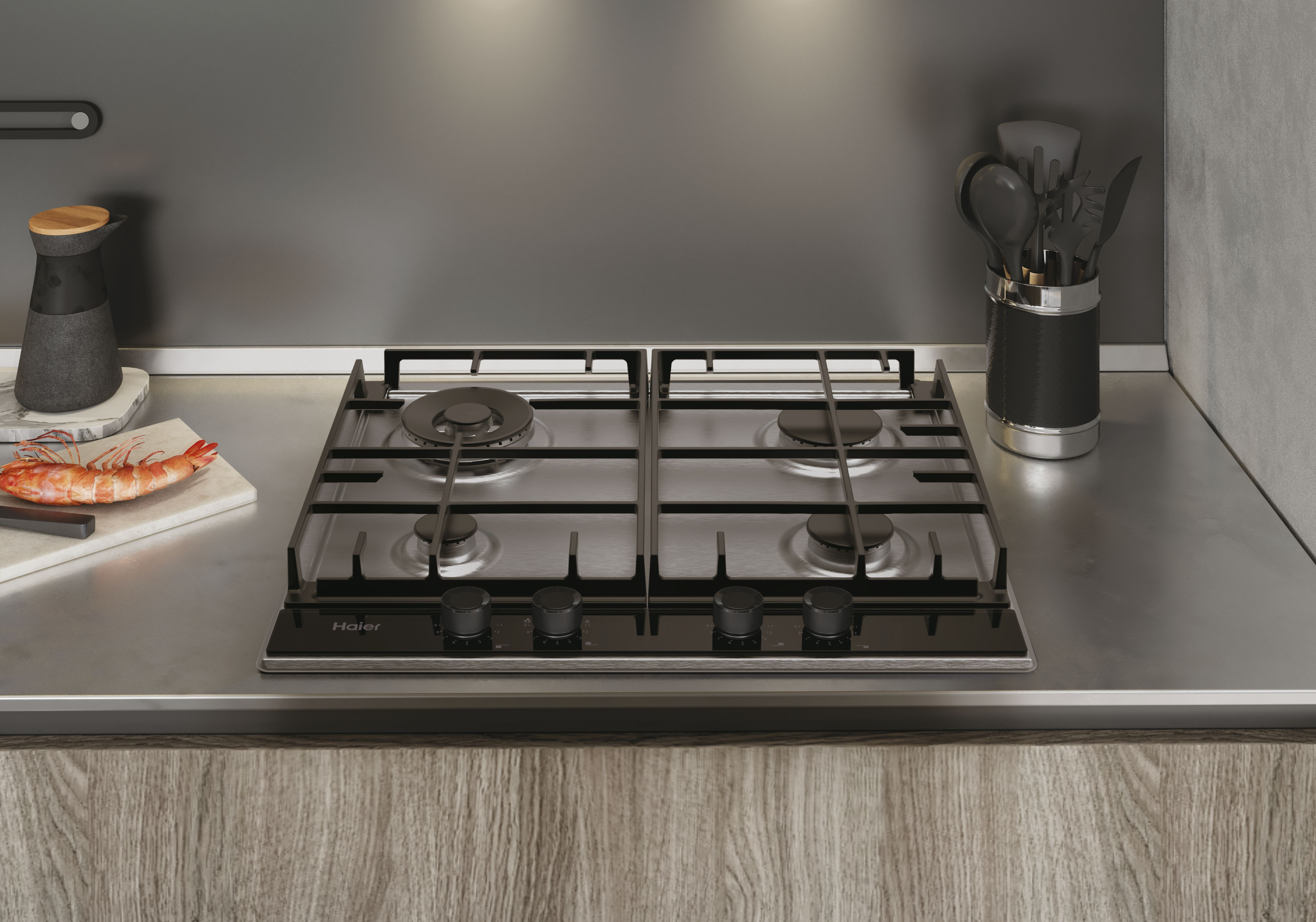 Un piano cottura a gas in acciaio inossidabile con quattro fuochi su un piano di lavoro in legno, con utensili da cucina e cibo.