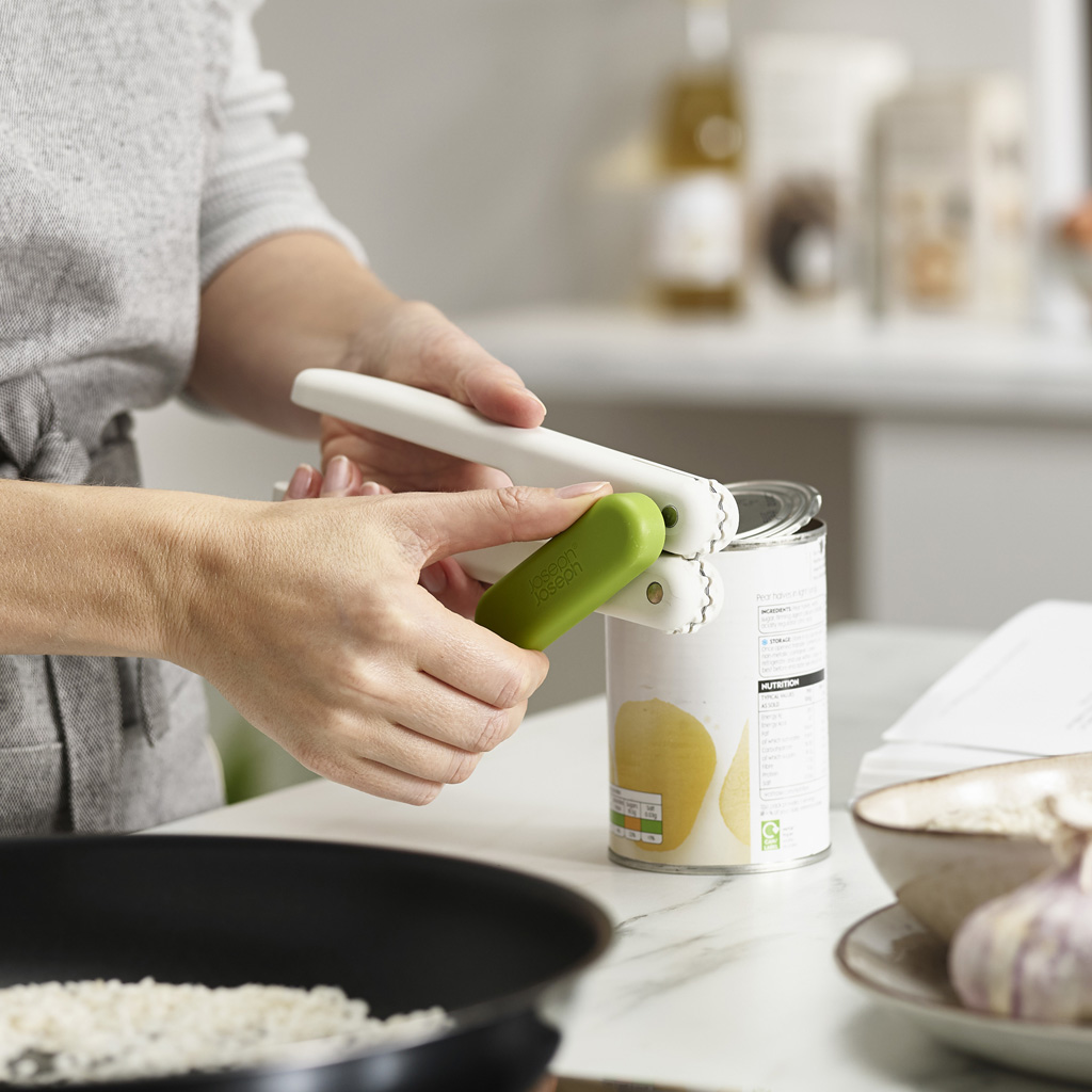 Una mujer usa un abrelatas blanco y verde en una cocina.