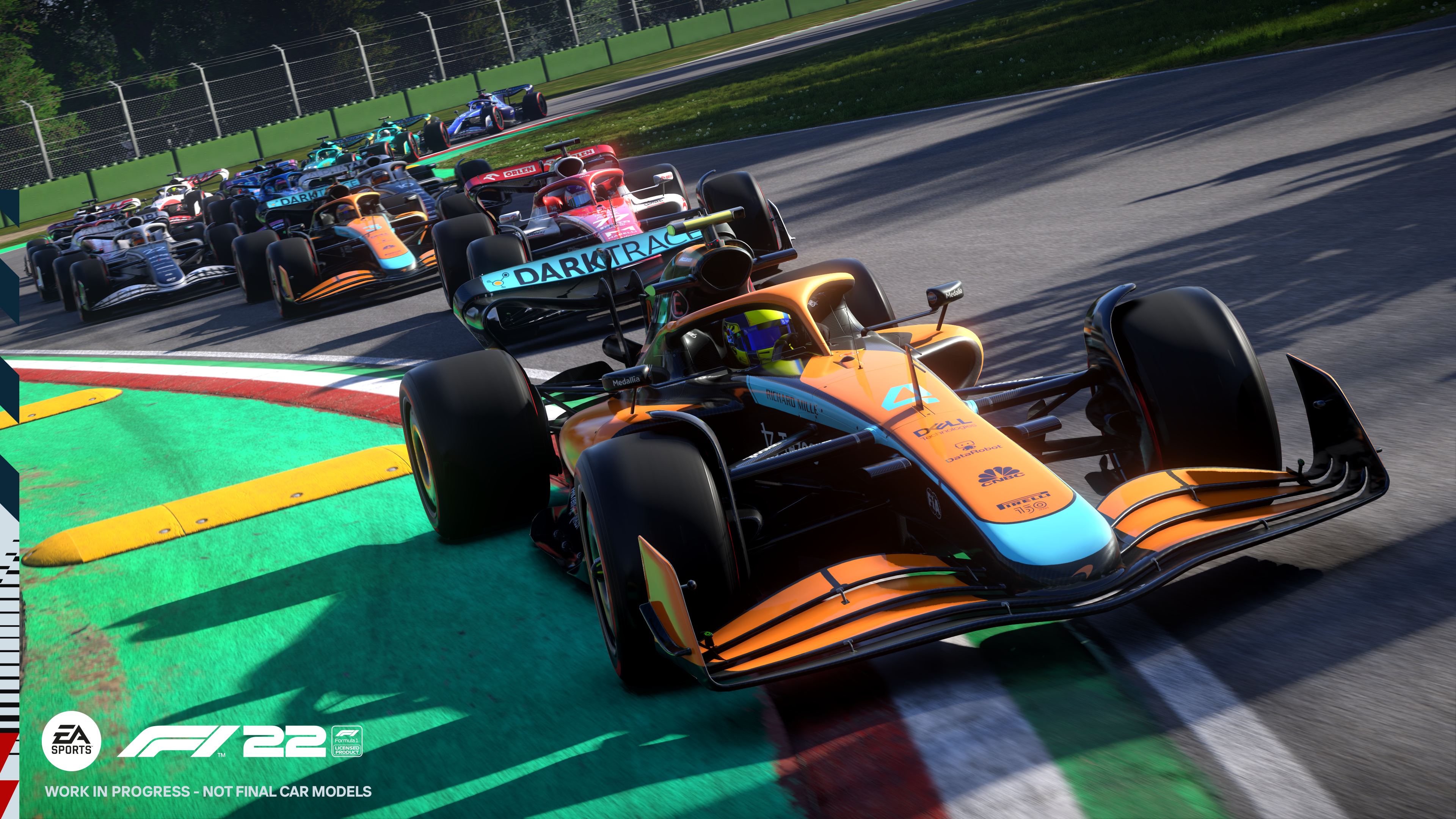 Samochody wyścigowe na torze, gra F1 22. Pomarańczowy samochód McLaren na pierwszym planie.