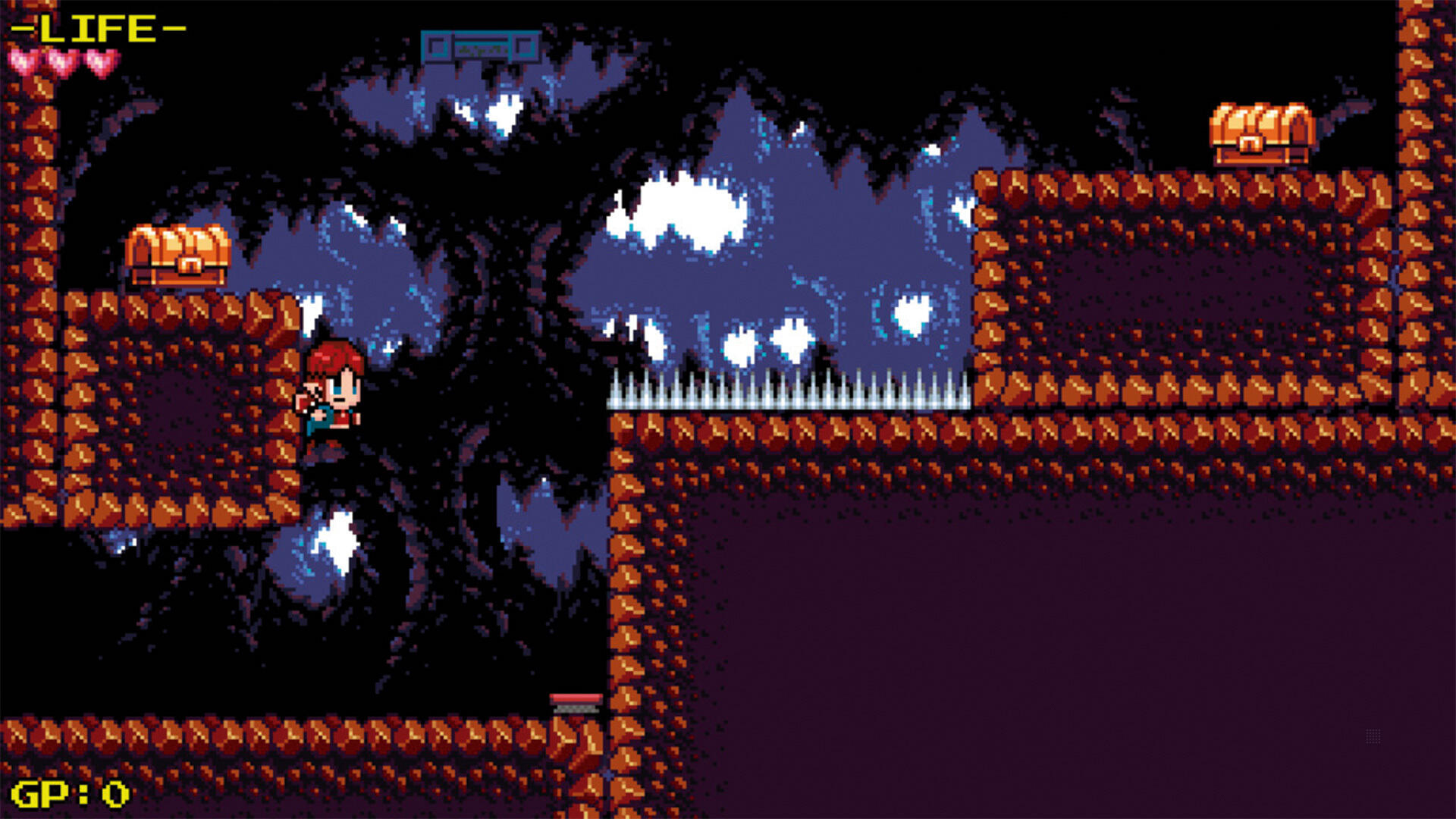 Scena gry w stylu pixel art z postacią w jaskini. Widoczne dwie skrzynie i kolce.