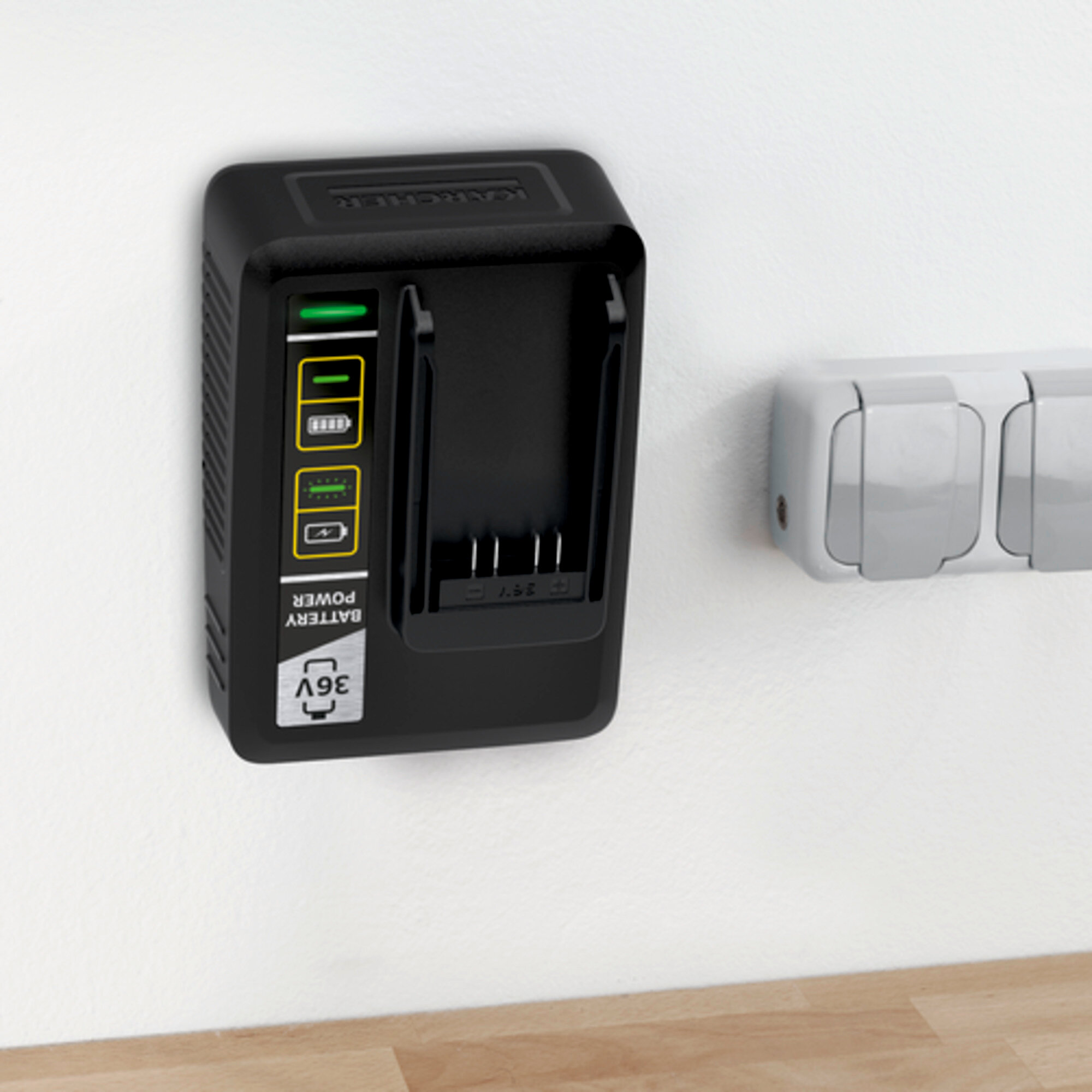 Ein schwarzes Batterieladegerät ist an einer weißen Wand montiert. Es ist ein 36-V-Ladegerät, neben einer Steckdose.