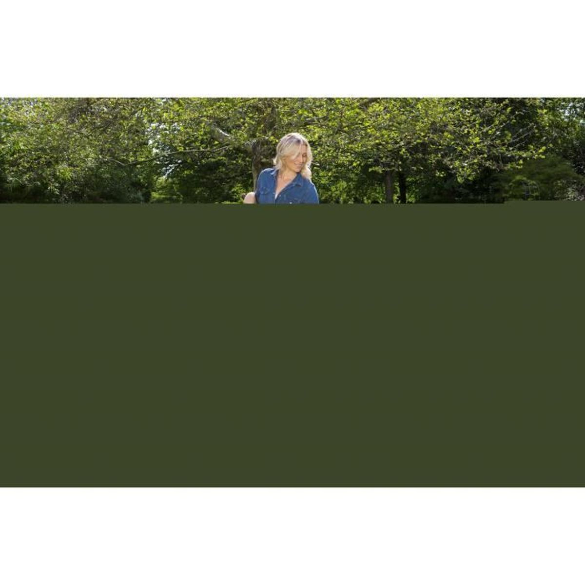 Eine Frau in einem Jeanshemd steht auf einer grünen Wiese. Bäume und blauer Himmel im Hintergrund.