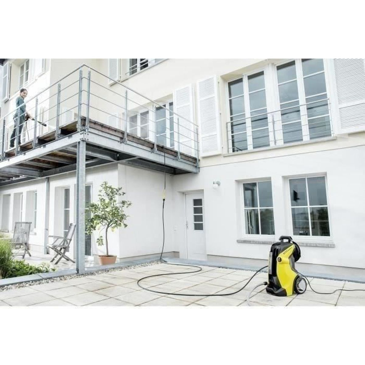 Eine Person benutzt einen Hochdruckreiniger an einem Haus. Gelber und schwarzer Hochdruckreiniger.
