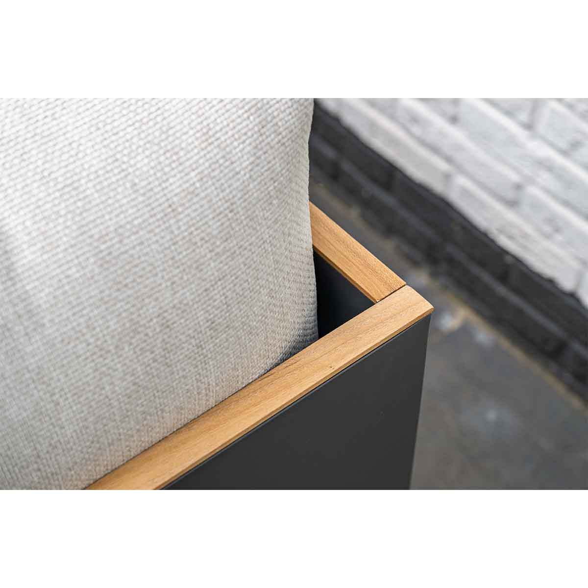 Gros plan d'un oreiller gris à l'intérieur d'une boîte noire avec une garniture couleur bois. Le fond est blanc.