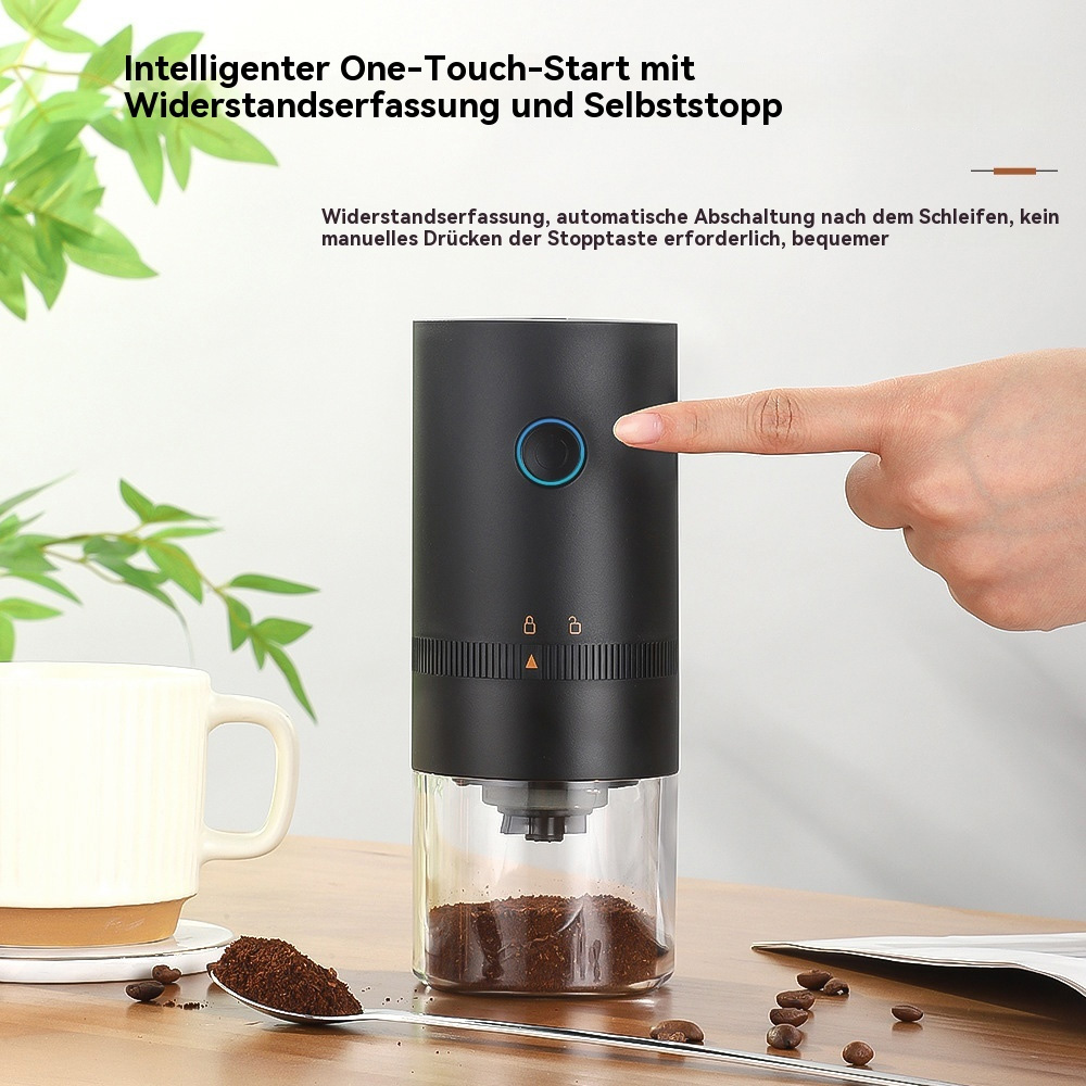 Eine Hand drückt einen Knopf auf einer Kaffeemühle. Kaffeesatz liegt auf einem Löffel und dem Tisch.