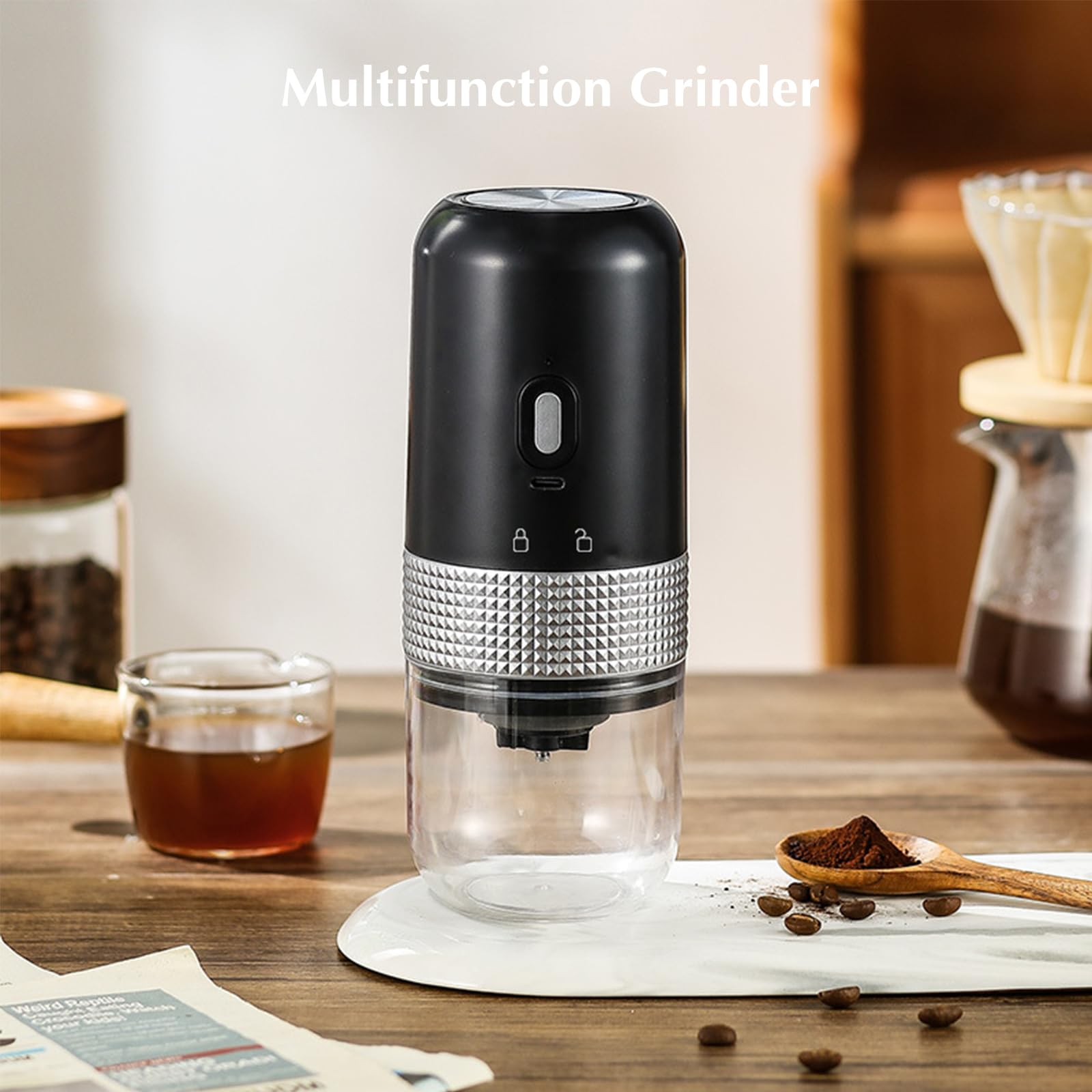 Schwarze und silberne Kaffeemühle mit klarem Boden. Kaffeebohnen und Zubehör im Hintergrund.