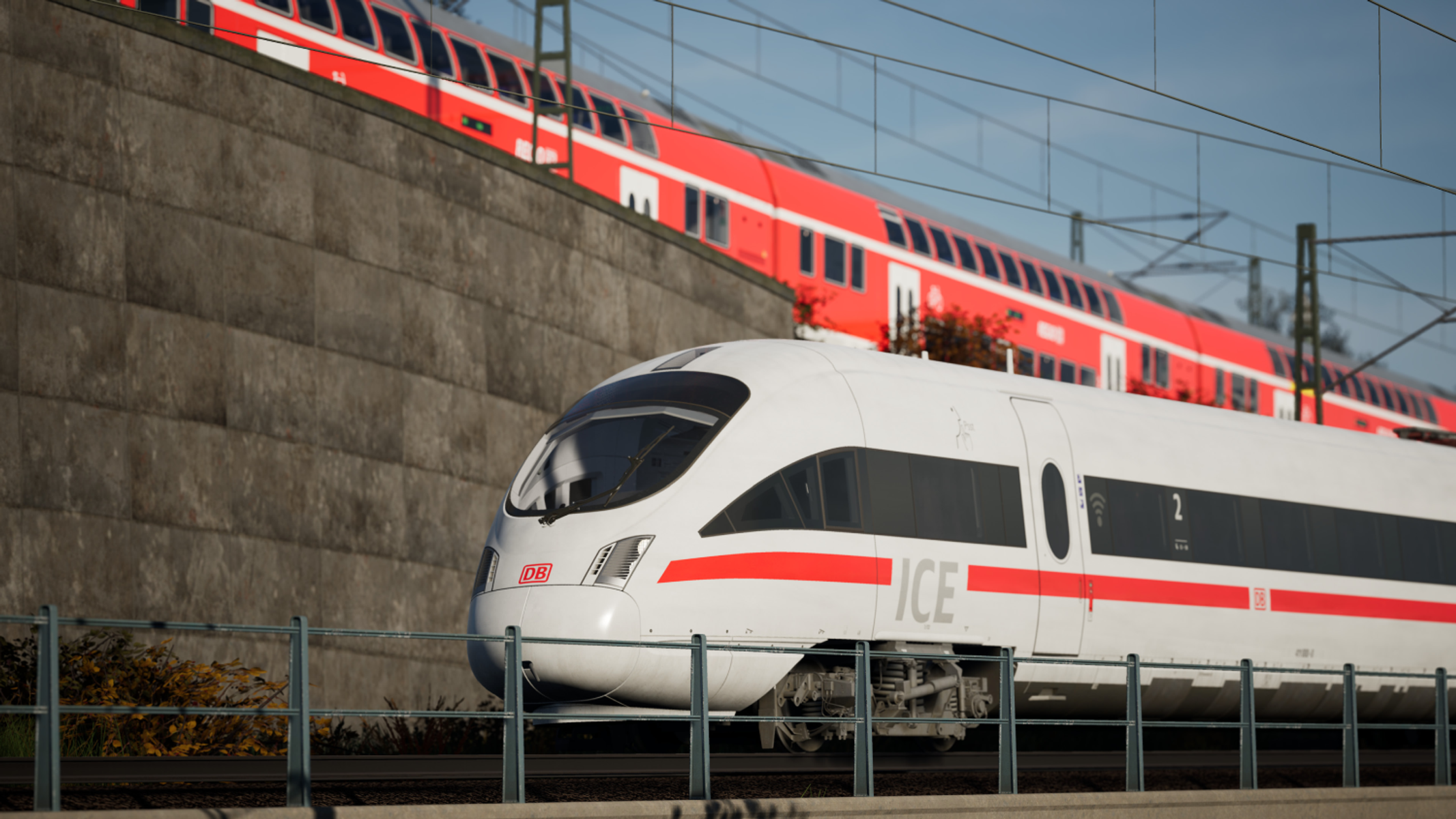 Biały pociąg ICE przejeżdżający obok czerwonego pociągu i betonowego muru.