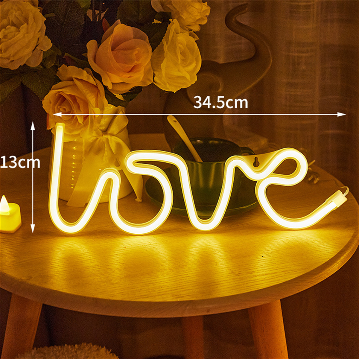 Ein Neon-Schild mit dem Wort LOVE in Gelb, auf einem Tisch mit Blumen und einer Tasse.